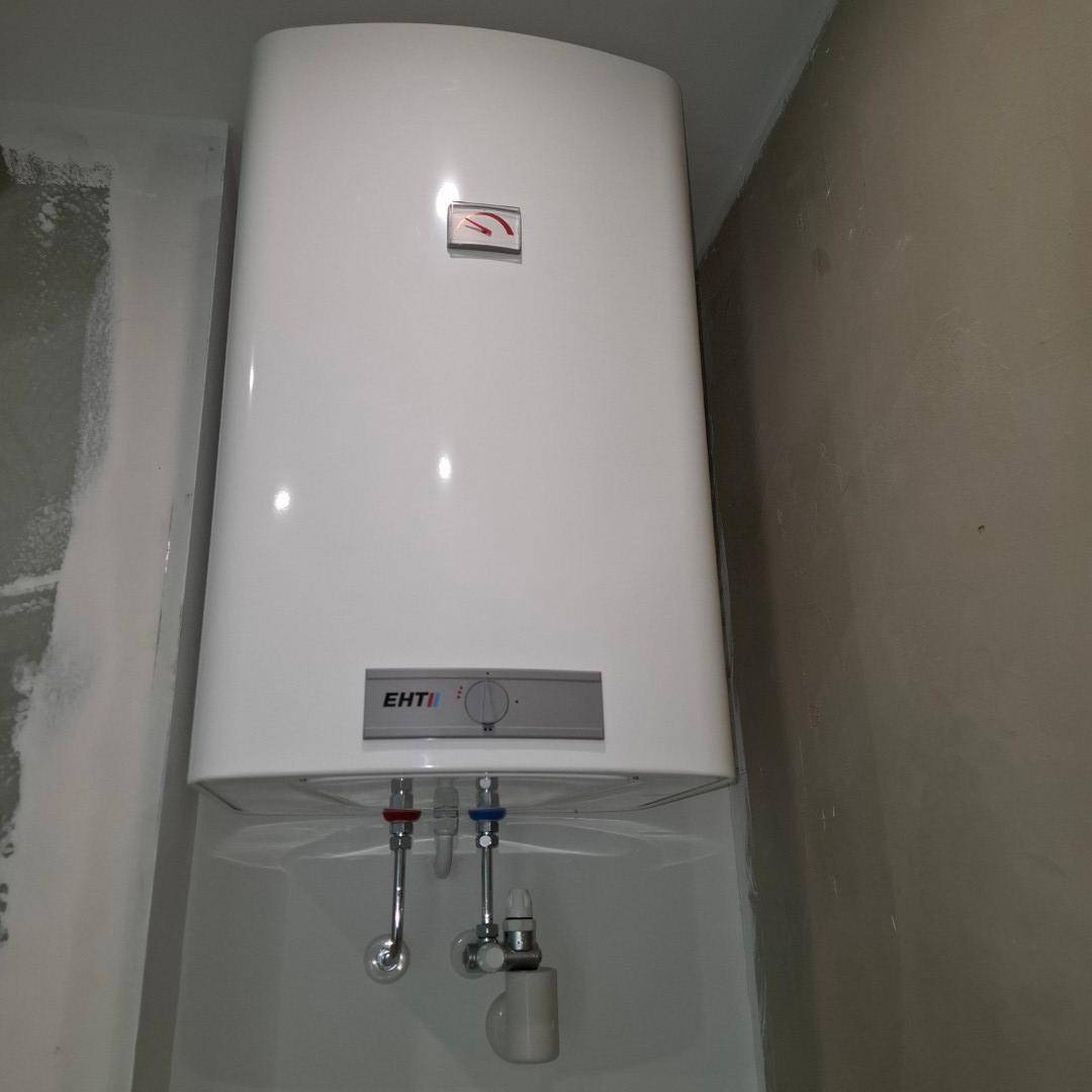Wandmontierter Warmwasserboiler in einem kleinen Raum, möglicherweise ein Badezimmer.