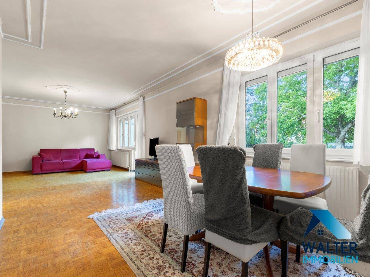 Heller Essbereich mit großem Holztisch, eleganten Stühlen und Blick ins Grüne.
