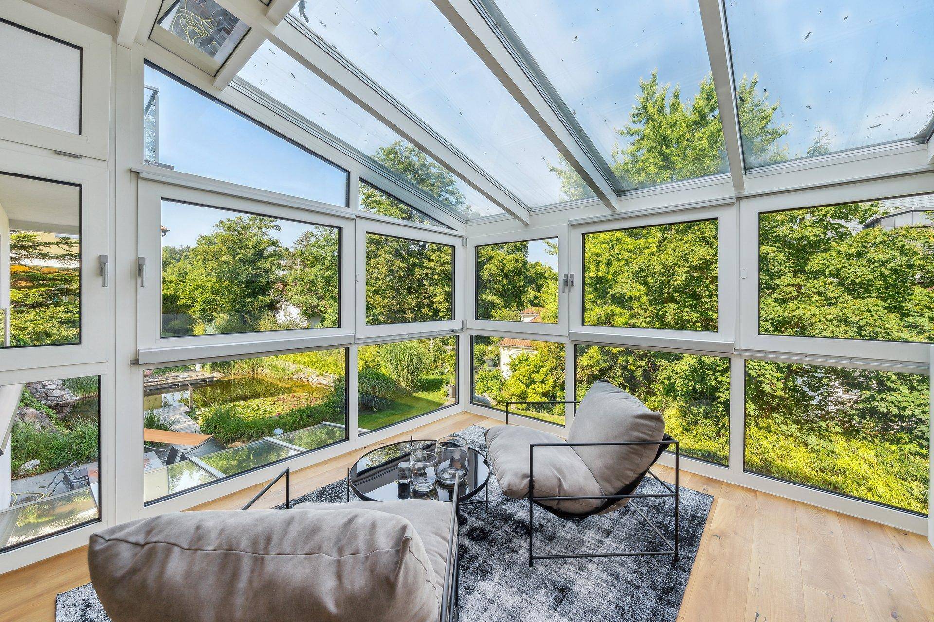 Lichtdurchfluteter Wintergarten mit Glasdach und weitem Blick auf die grüne Umgebung.