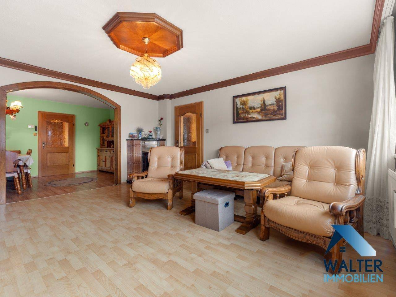 Geräumiges Wohnzimmer mit bequemen Ledersofas und Holzboden, verbunden mit dem Essbereich.
