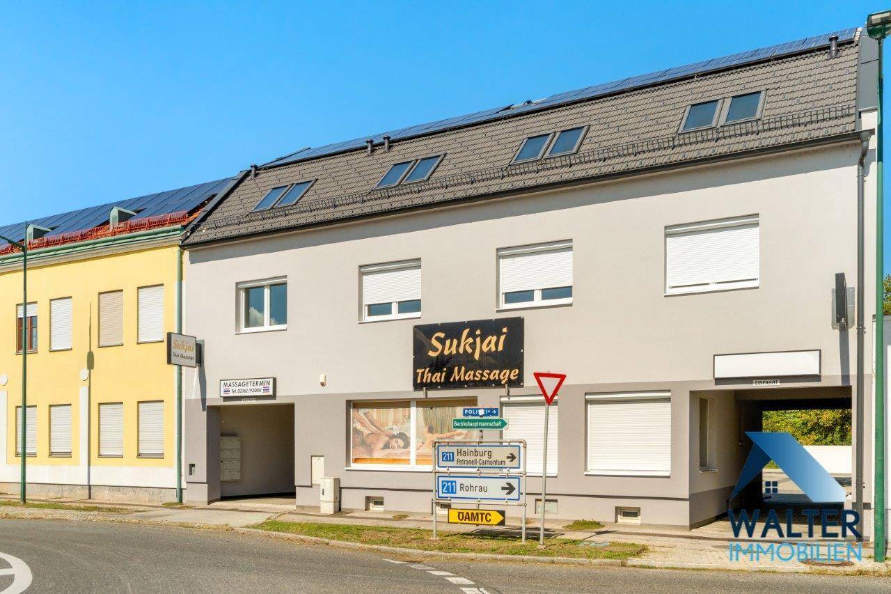 Mehrstöckiges Gebäude mit Geschäften im Erdgeschoss und Wohnungen darüber, mit Solarpaneelen auf dem Dach.