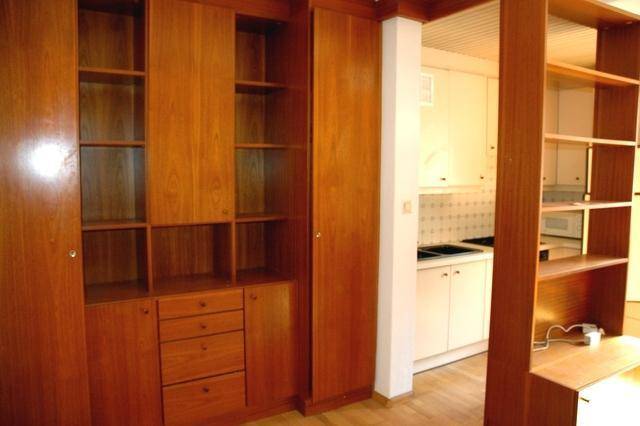 Detailansicht der Holzregale und Einbauschränke mit Blick auf die kleine Küchenzeile.