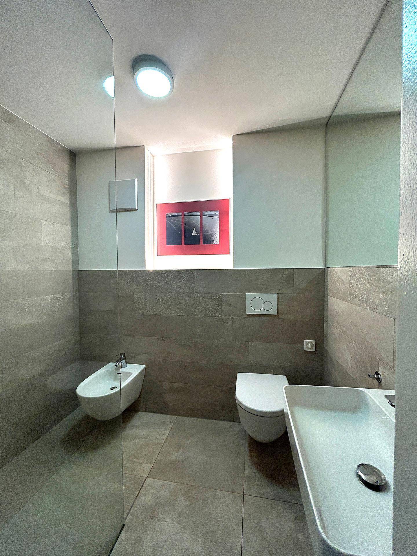 Modernes Badezimmer mit Bidet, wandhängendem WC, Aufsatzwaschbecken und großen Spiegeln.