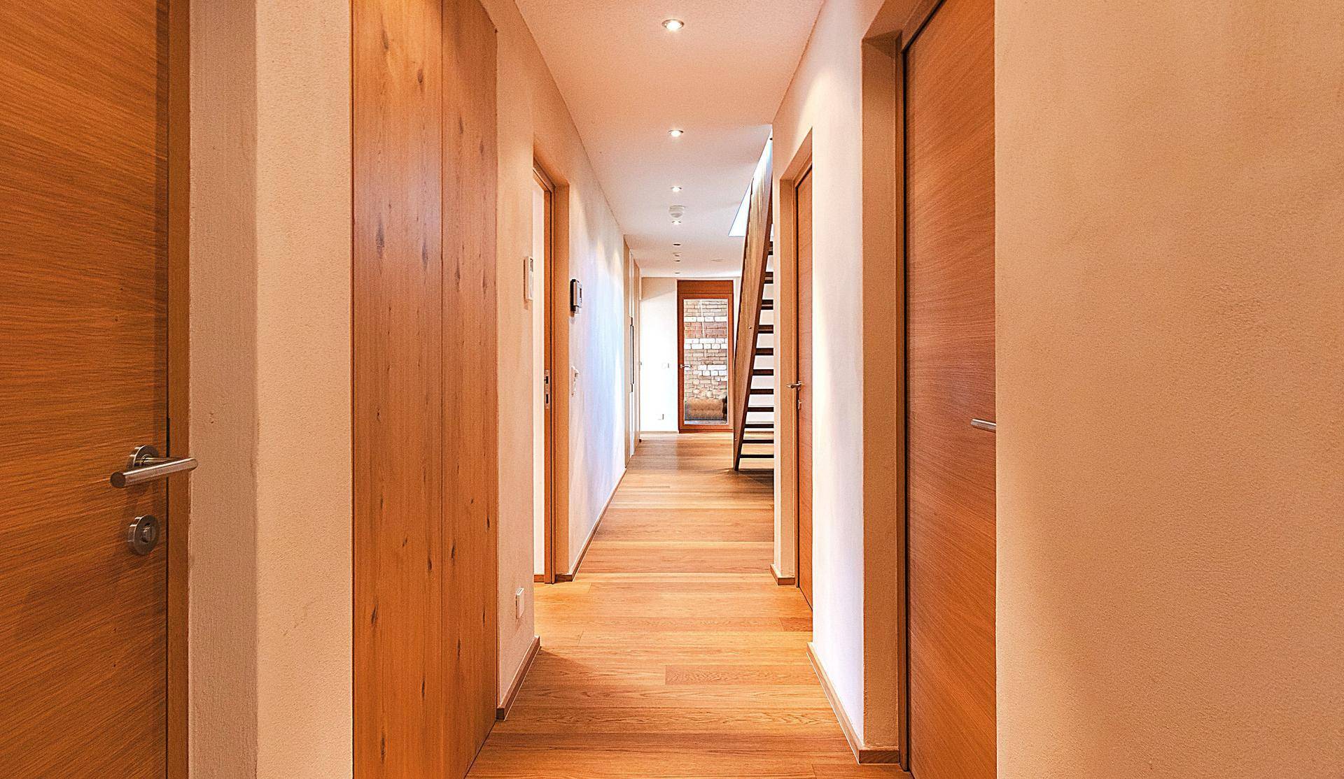 Langer, heller Flur mit Holzboden und modernen Holztüren, der zu weiteren Räumen führt.