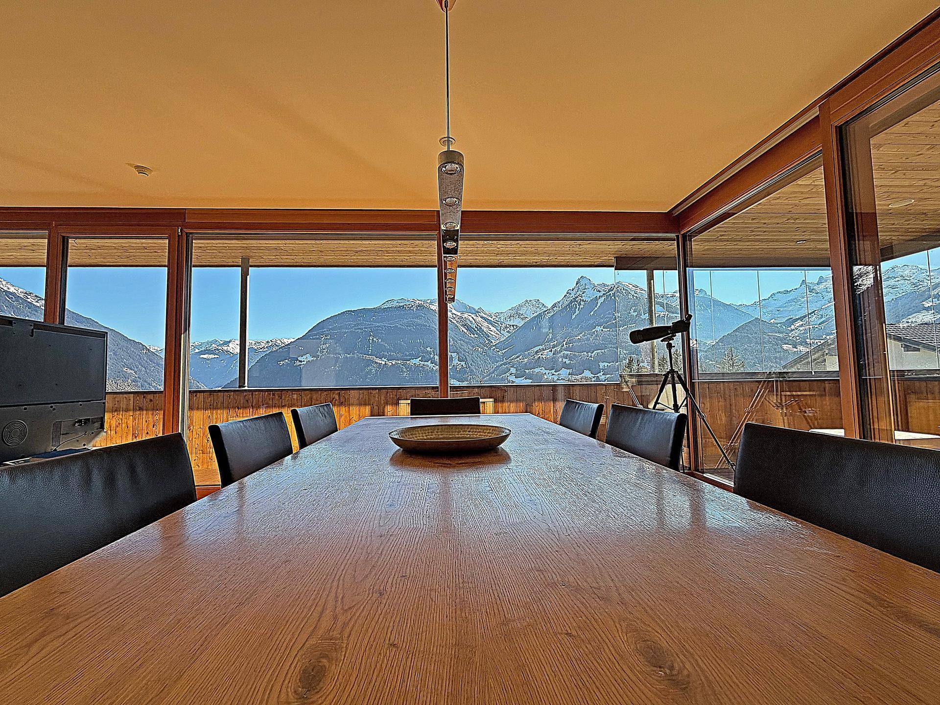 Heller Essbereich mit großem Holztisch und raumhohen Fenstern mit beeindruckendem Bergblick.