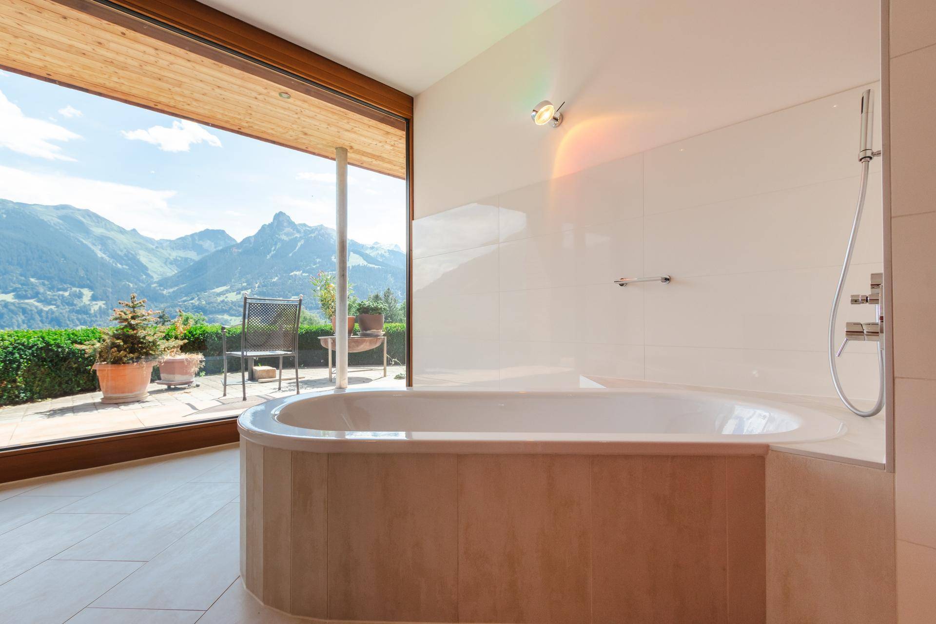 Elegantes Badezimmer mit Badewanne und Panoramafenster, das einen direkten Blick auf die Berge ermöglicht.