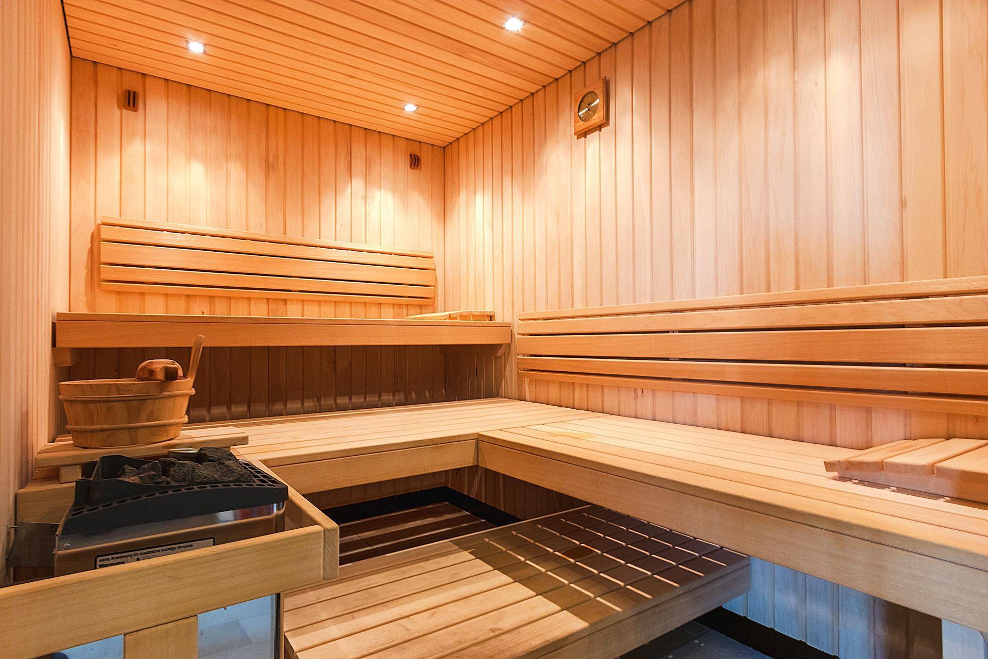 Traditionelle Holzsauna mit mehreren Bänken und einem Saunaofen für entspannende Momente.