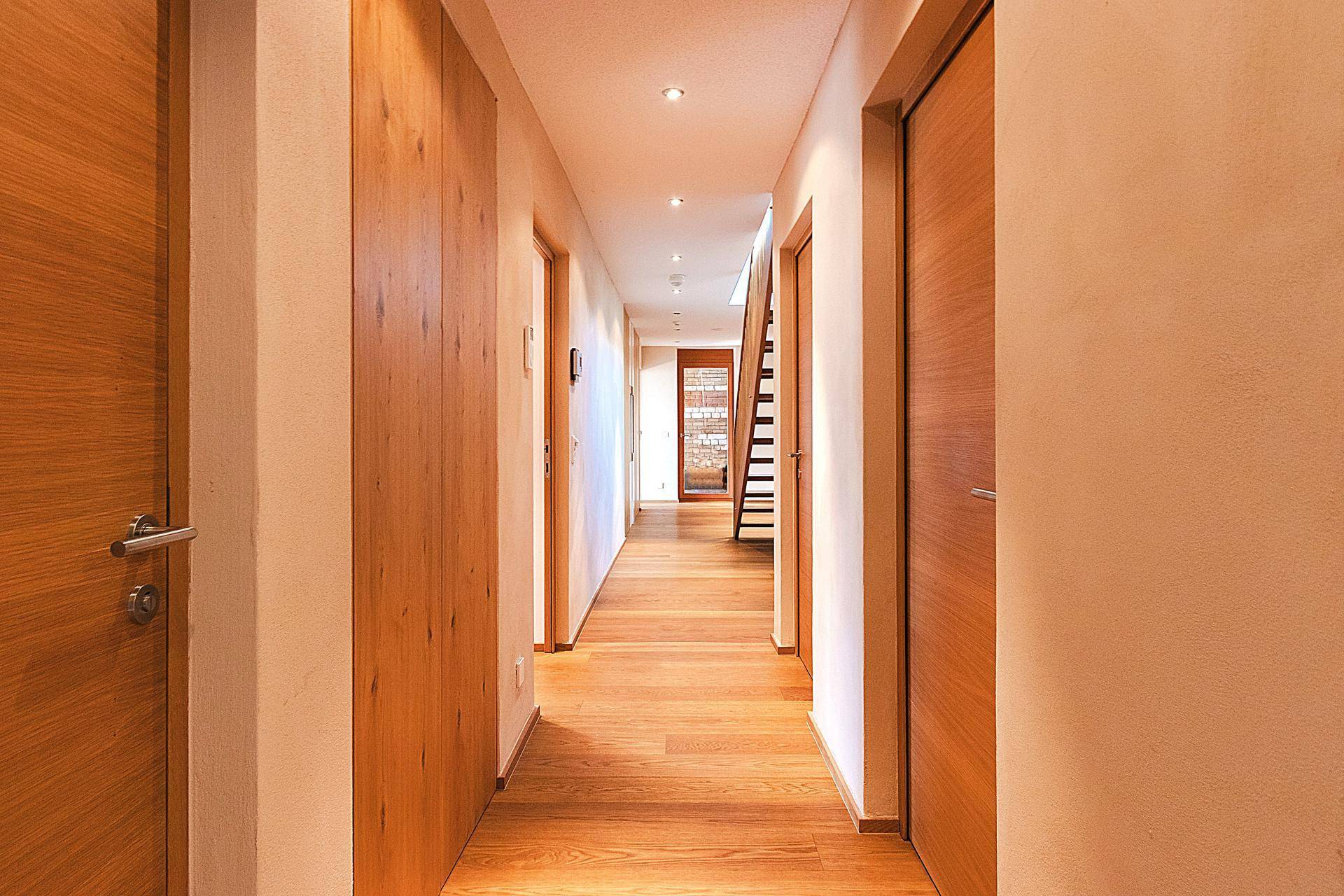 Heller Flur mit Holzboden und Holztüren, der zu weiteren Räumen und einer Treppe führt.