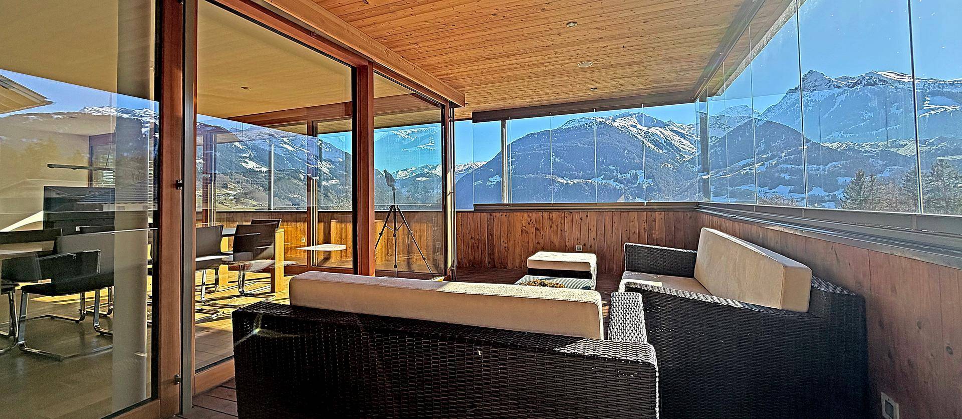 Verglaste Loggia mit bequemen Sitzgelegenheiten und spektakulärem Blick auf die Berge.