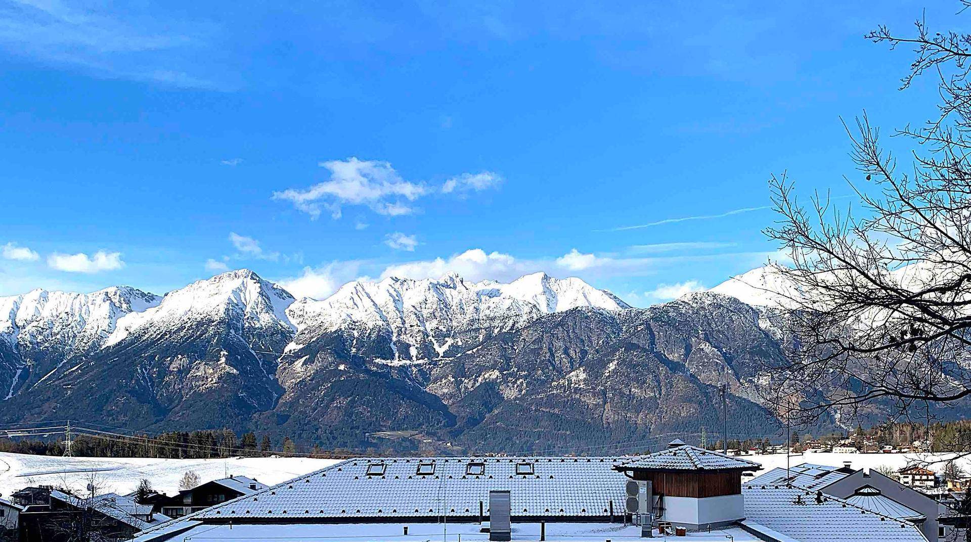 Atemberaubender Panoramablick auf schneebedeckte Berge und eine winterliche Landschaft mit Dächern.