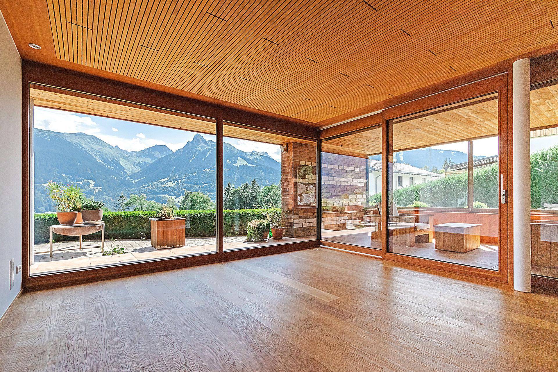 Heller Wohnraum mit Holzboden und raumhohen Fenstern, die einen weiten Bergblick bieten.