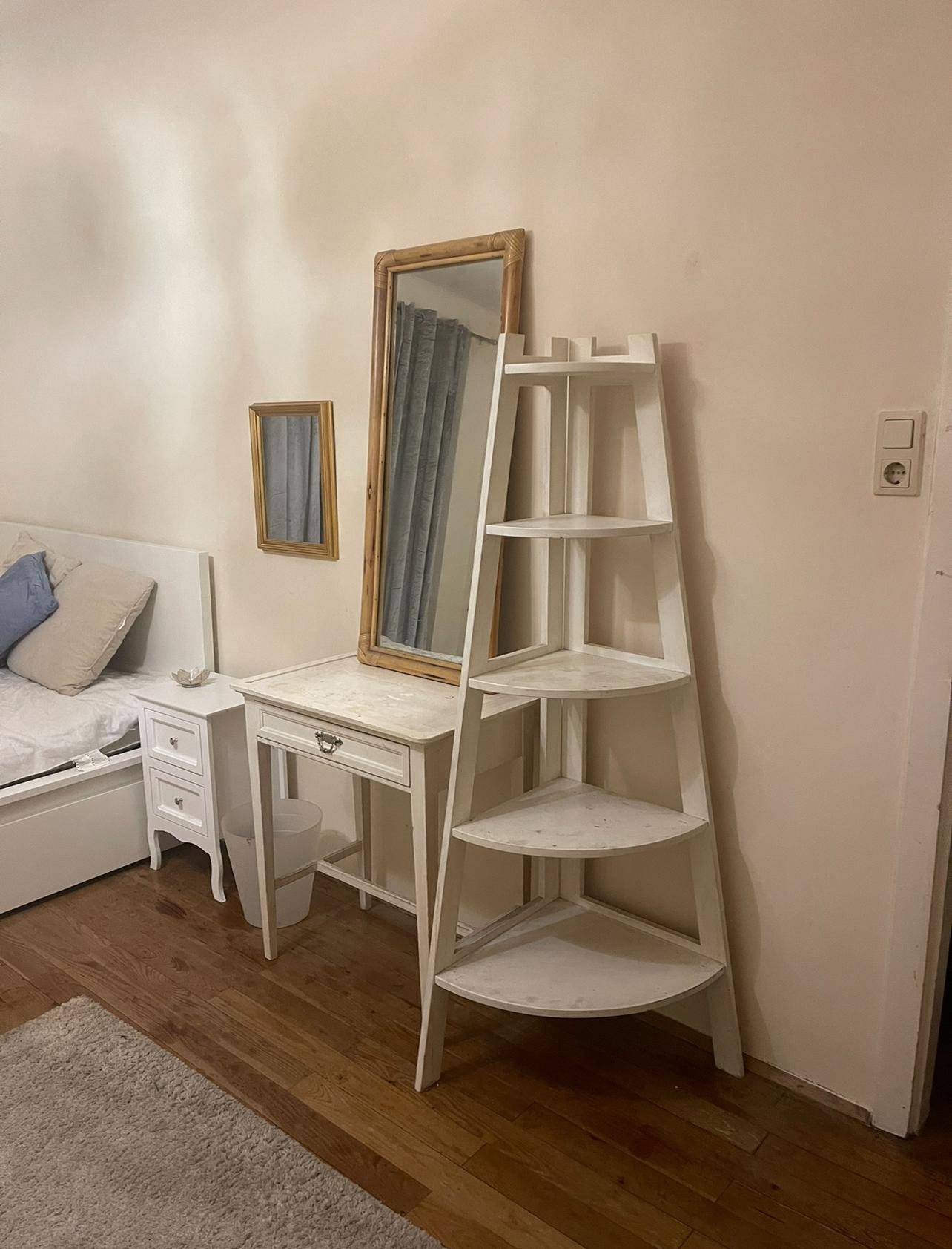 Schlafzimmer mit Spiegel, Schreibtisch und Eckregal, ergänzt die funktionale Einrichtung.