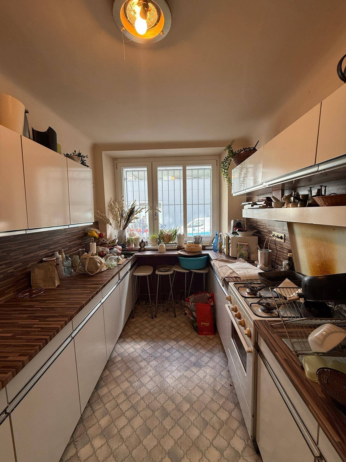 Küche mit Fenster, Gasherd und weißen Schränken, ideal für die tägliche Essenszubereitung.