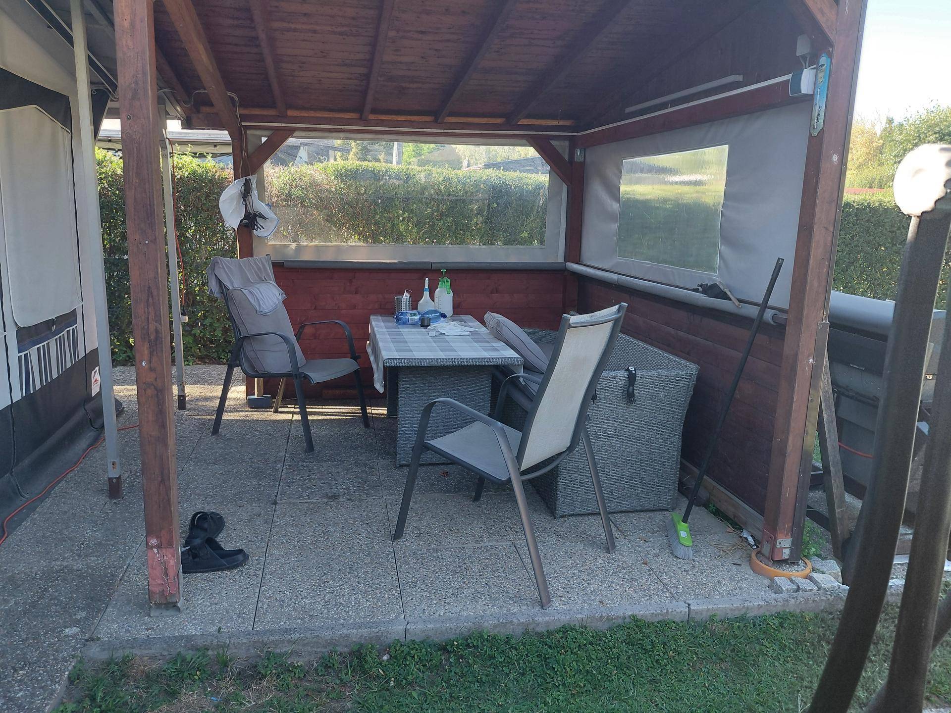 Überdachter Sitzbereich im Freien mit Tisch und Stühlen, ideal für entspannte Stunden im Garten.