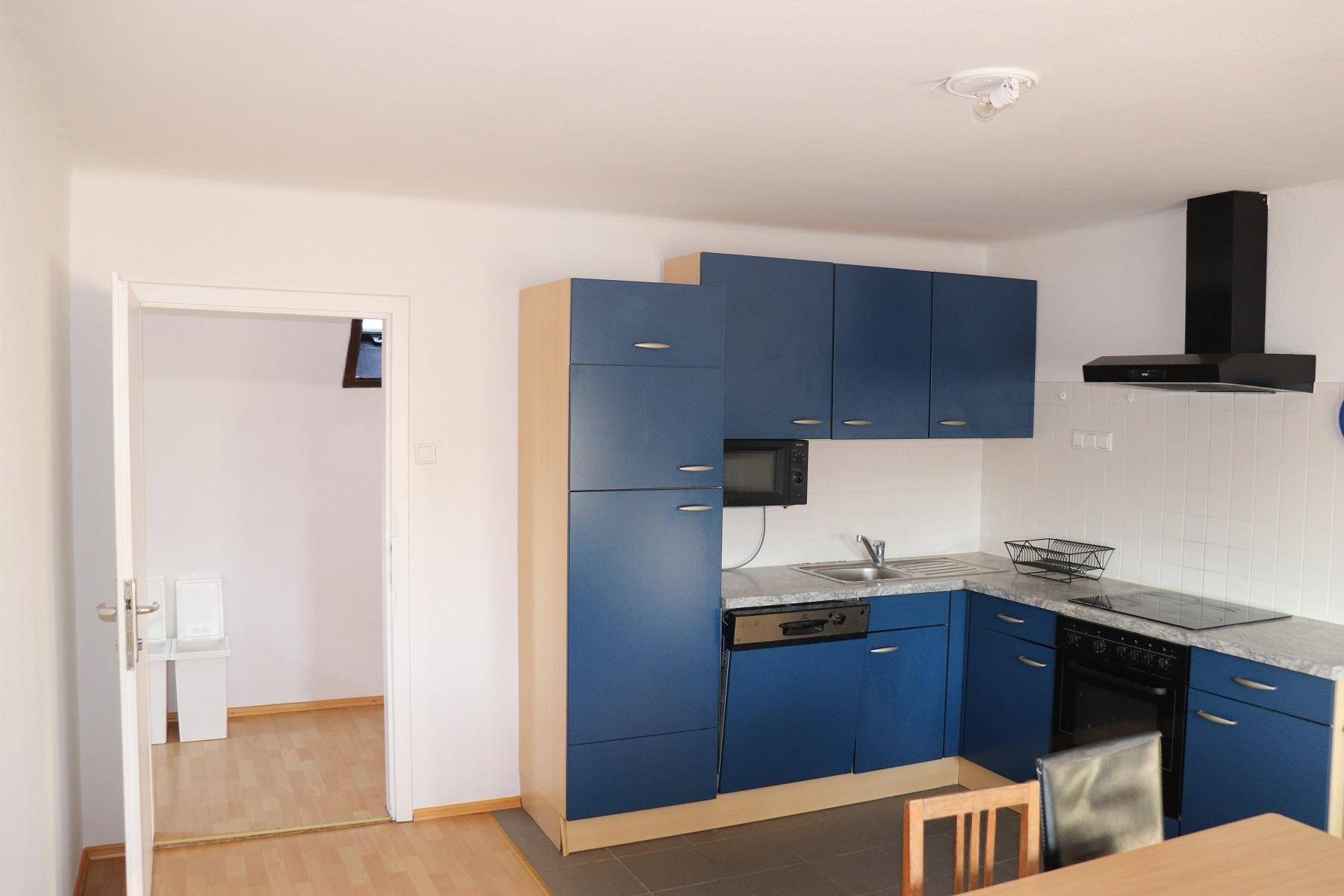 Moderne Küche mit blauen Schränken, integrierten Geräten und einem kleinen Essbereich.