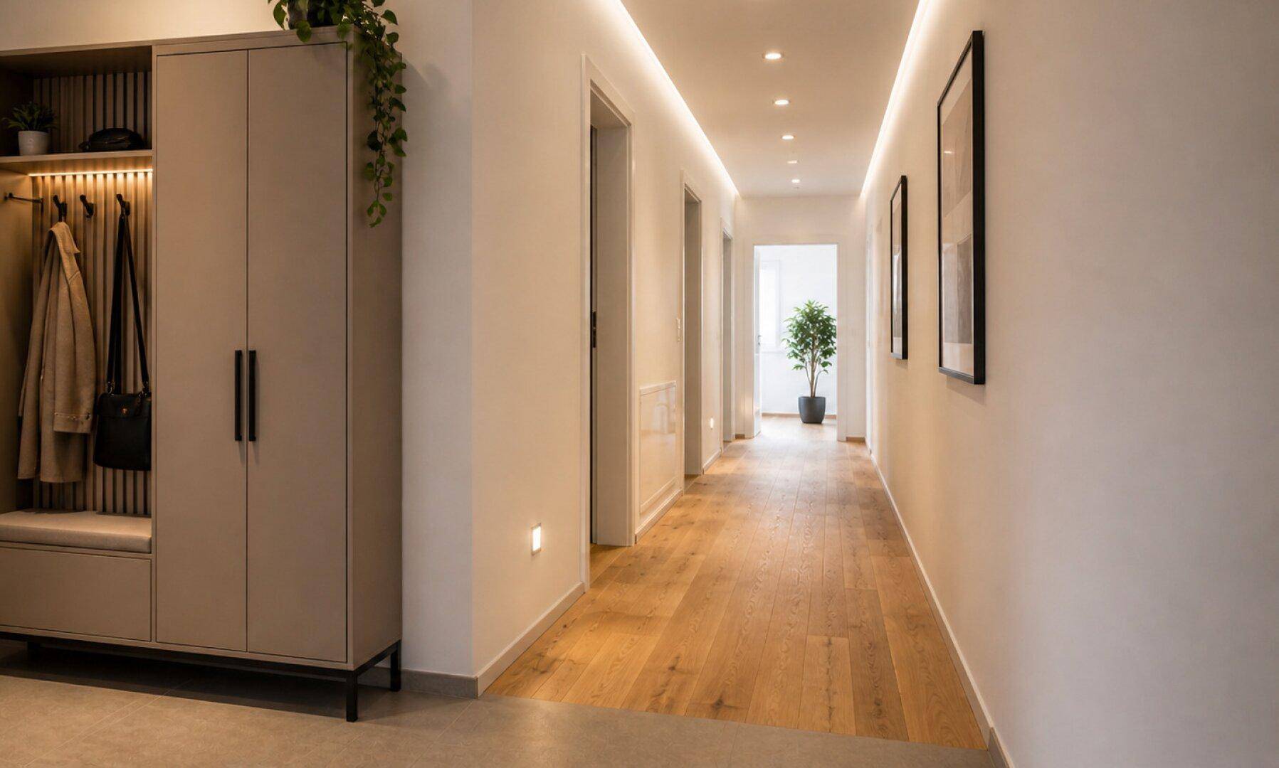 Heller Flur mit Holzfußboden, moderner Garderobe und indirekter Beleuchtung.