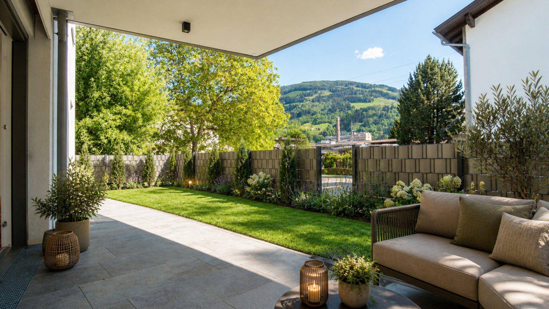 Überdachte Terrasse mit bequemen Gartenmöbeln, Rasenfläche und Bergblick.