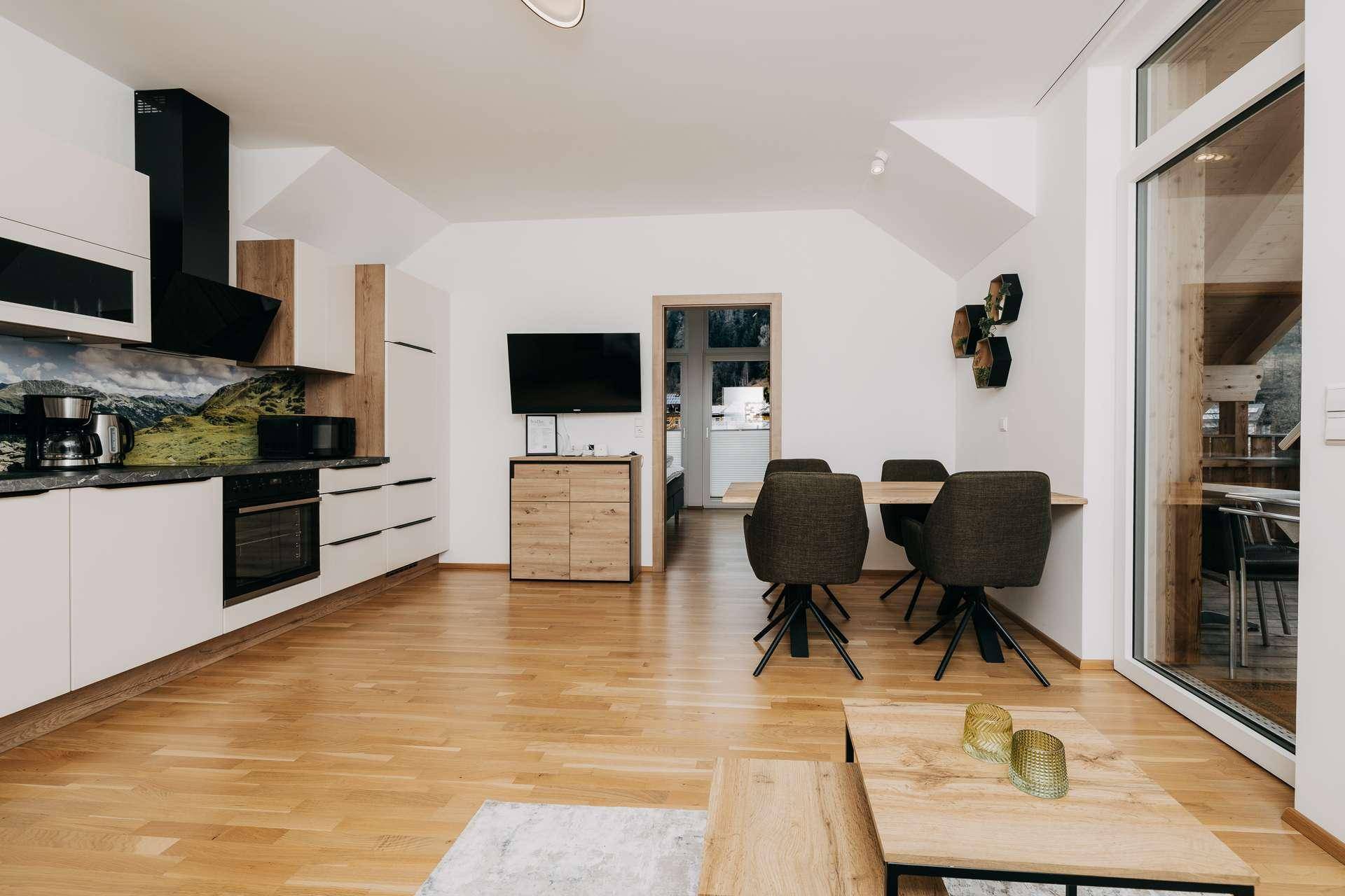 Geräumiger Wohn-Essbereich mit moderner Einbauküche, Esstisch und hellem Holzfußboden.