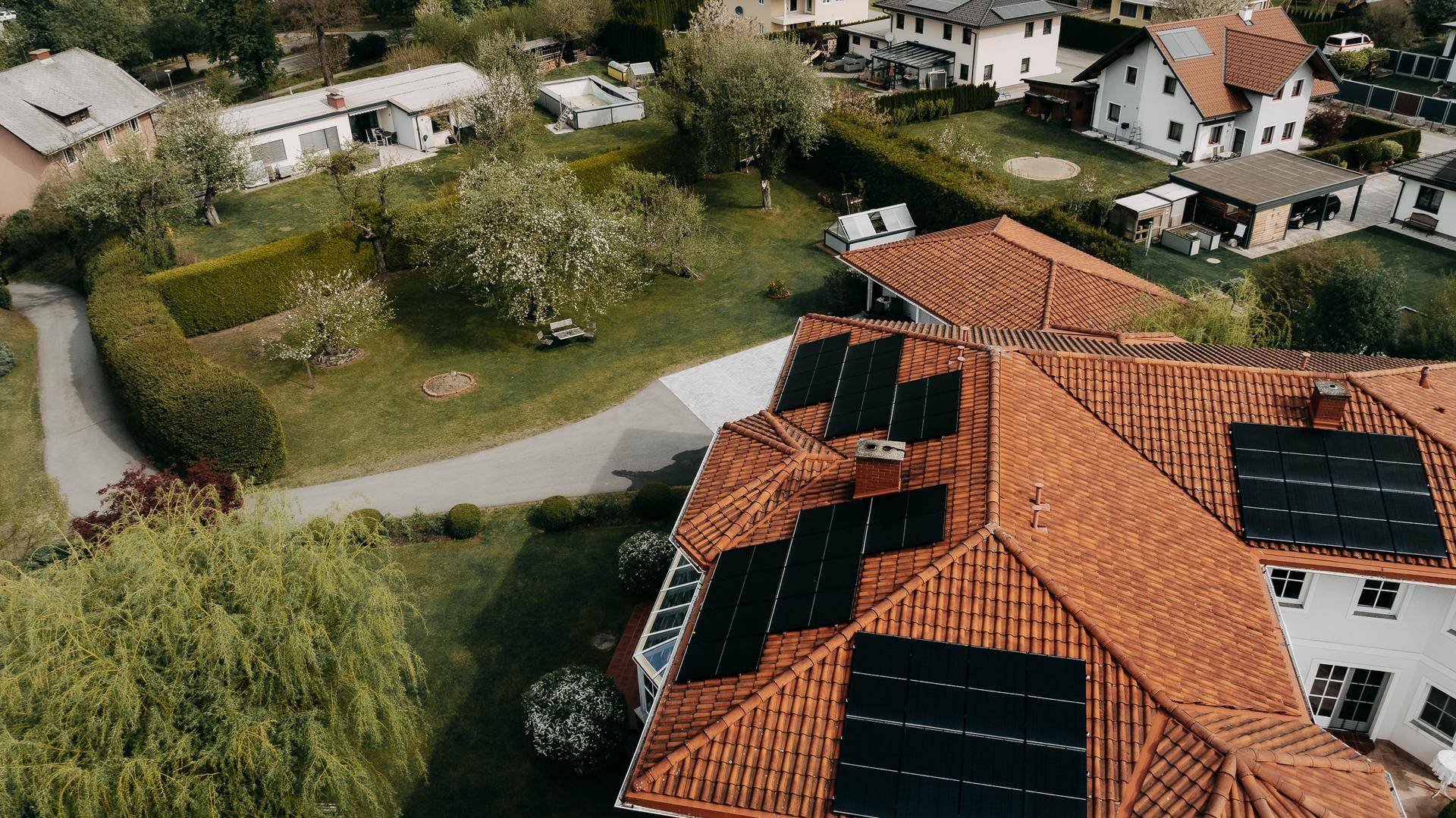 Nahaufnahme des Daches mit zahlreichen Photovoltaikmodulen und Blick auf die umliegende Bebauung.