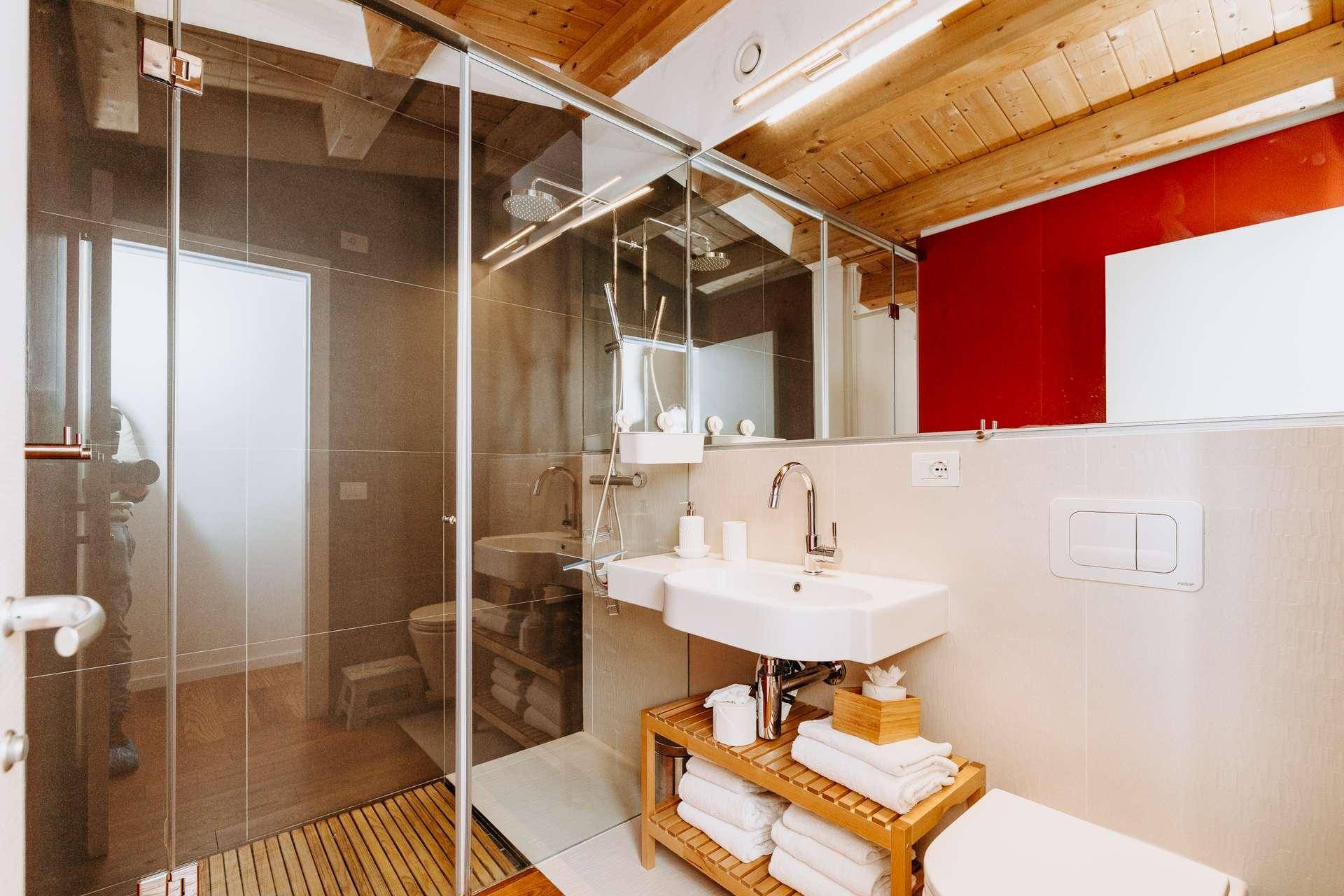 Modernes Badezimmer mit Glasdusche, Einzelwaschbecken und Holzbalkendecke.