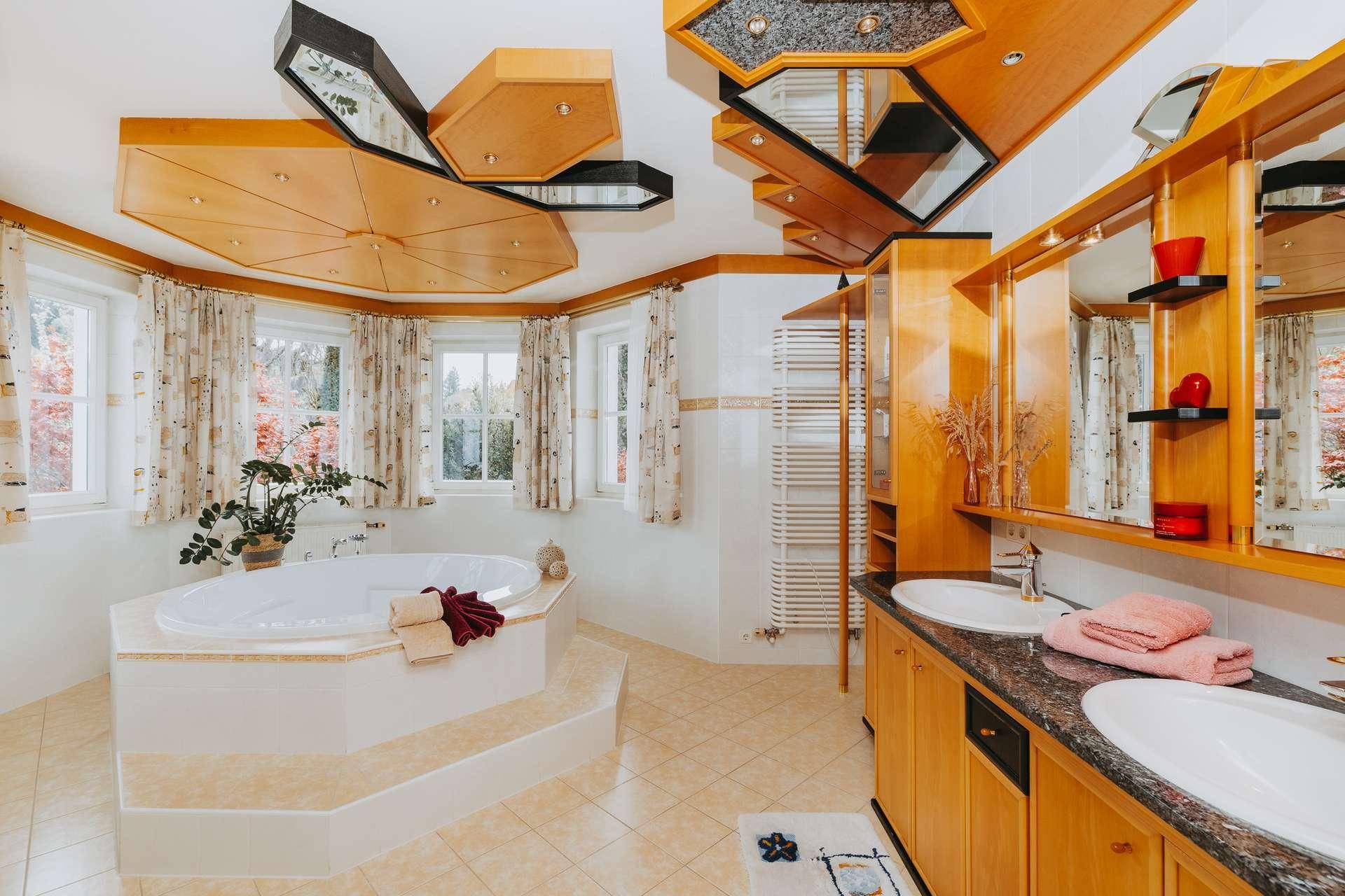 Großes Badezimmer mit Doppelwaschbecken, Eckbadewanne und Holzdecke.
