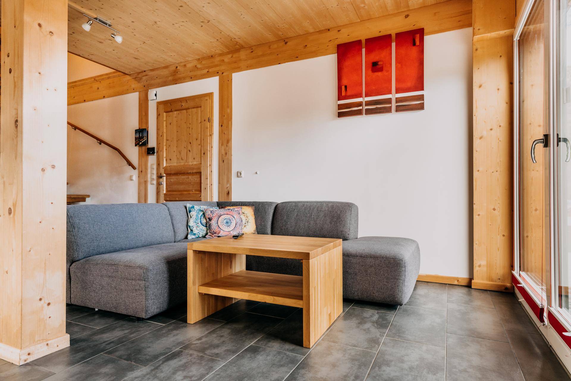 Gemütliches Wohnzimmer mit Holzbalken, Fliesenboden und moderner Einrichtung.