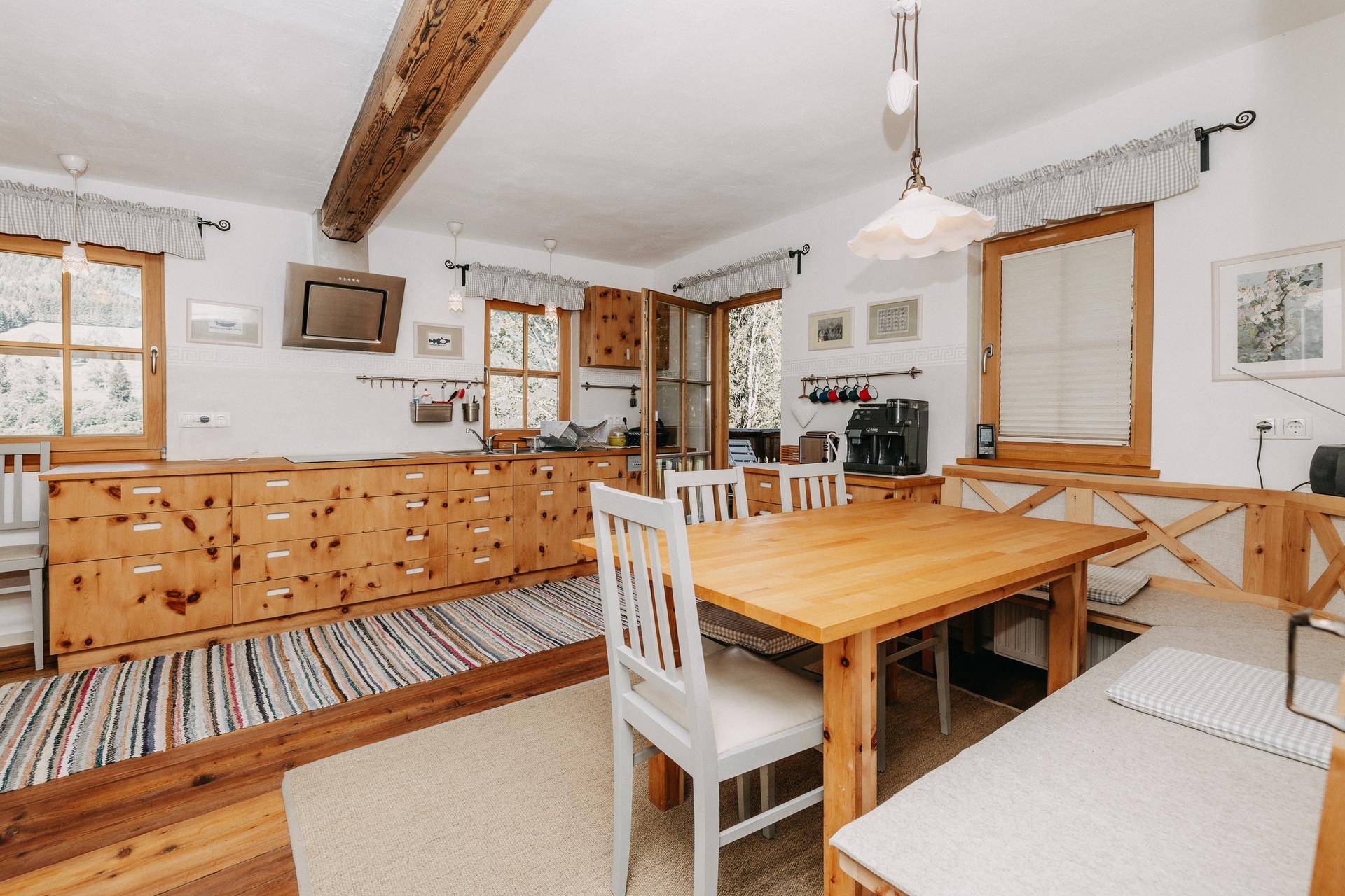 Helle Wohnküche mit Holztisch, Eckbank und traditionellen Holzschränken.