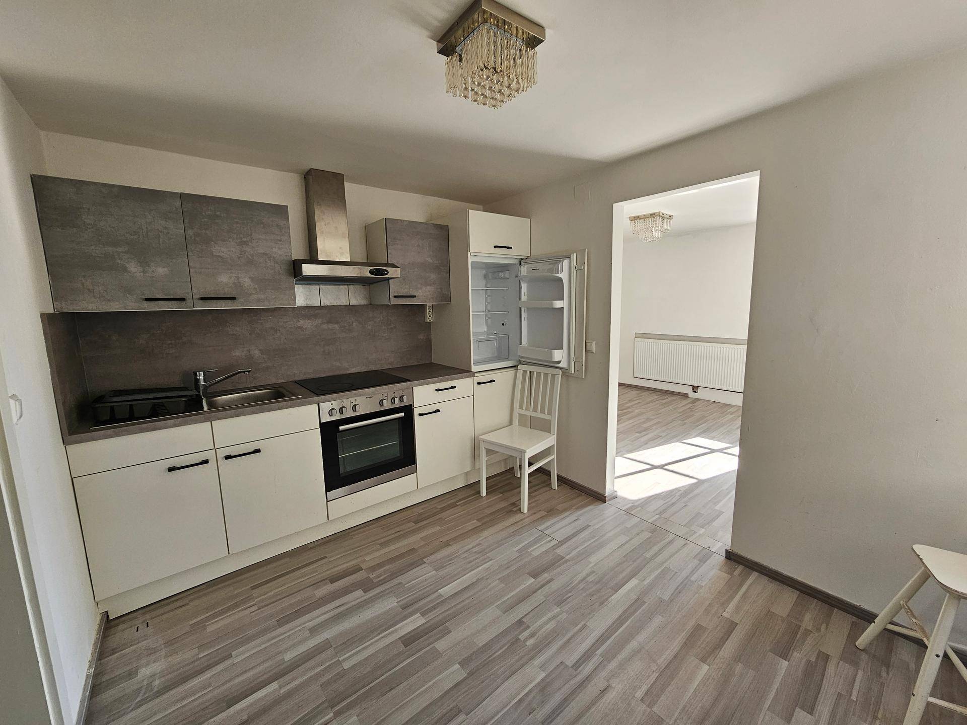 Moderne Einbauküche mit hellen Fronten, integrierten Geräten und Blick in einen weiteren Raum.