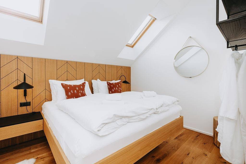 Helles Schlafzimmer im Dachgeschoss mit Holzboden, Dachfenster und modernem Design.
