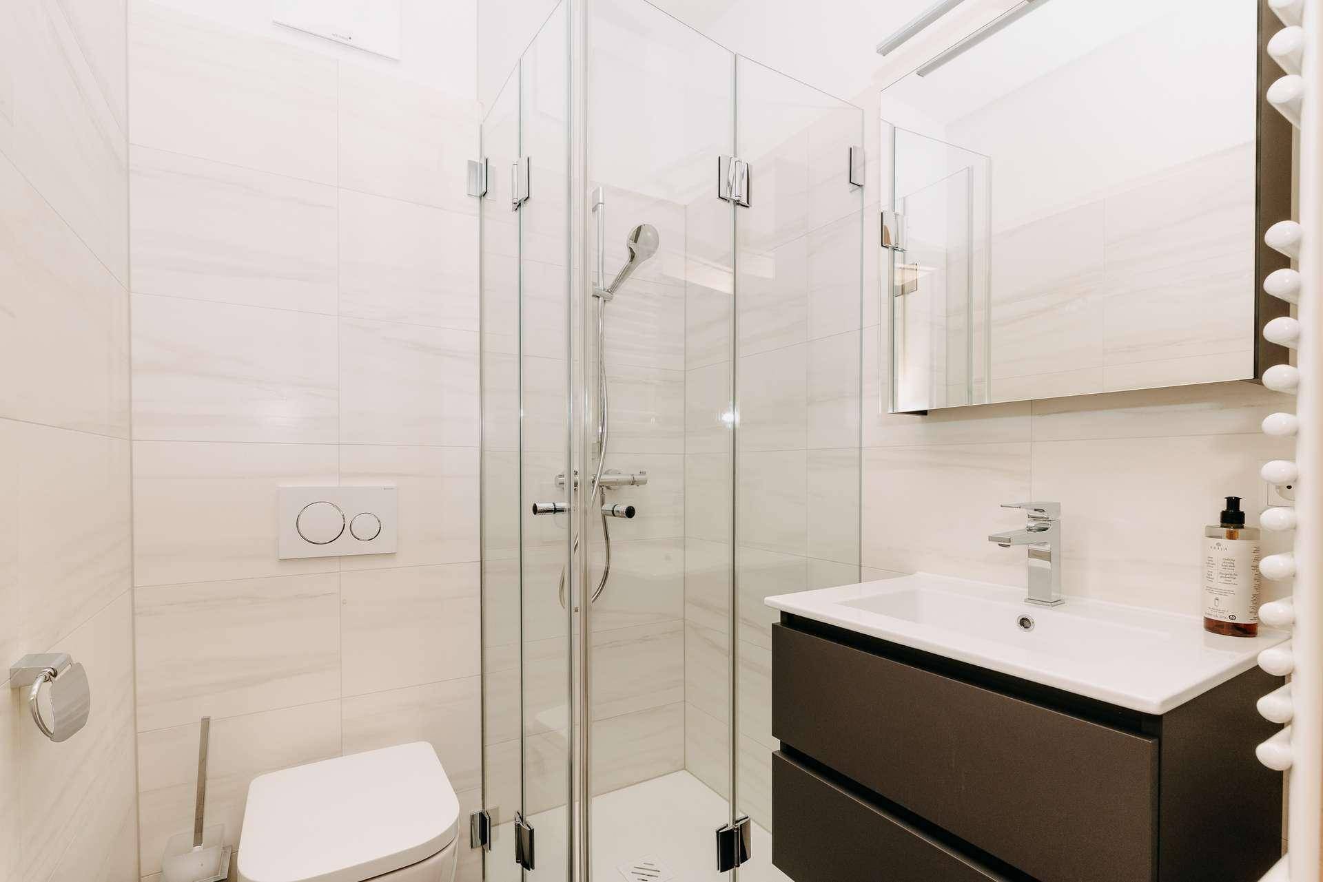 Helles Badezimmer mit Duschkabine, modernem Waschtisch und Wand-WC.