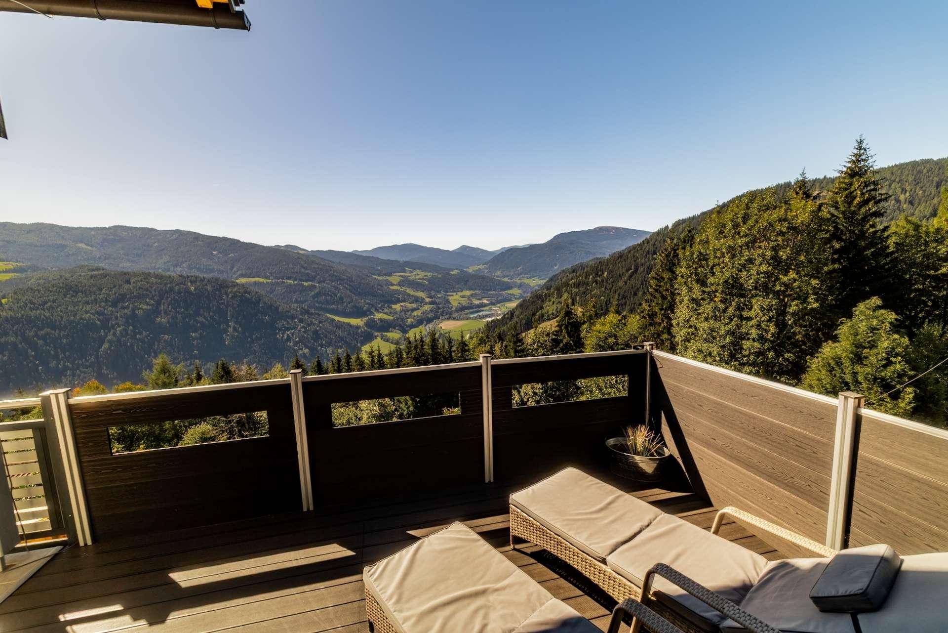 Sonnenterrasse mit Liegestühlen und weitem Blick über die bewaldeten Berge.