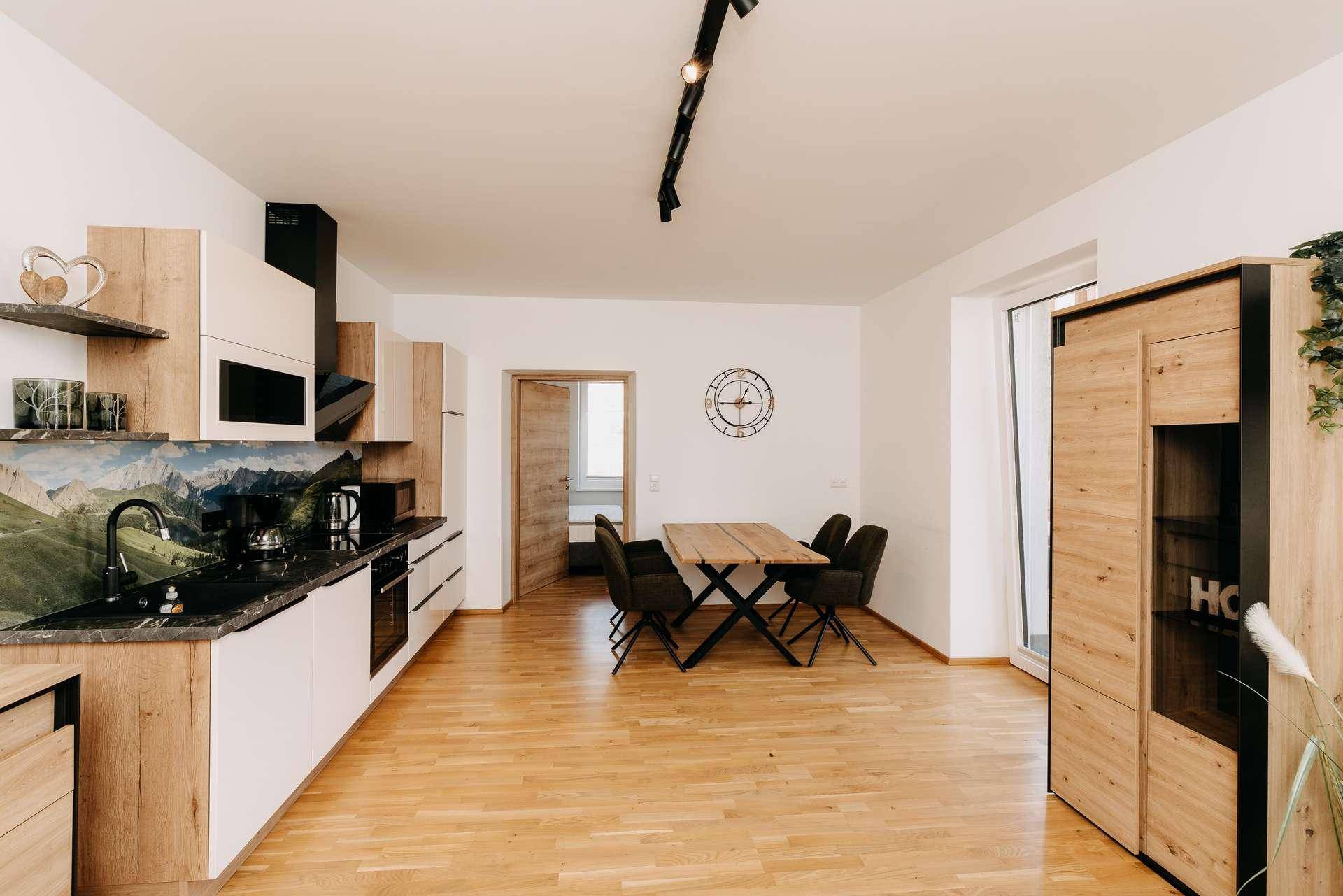 Offener Wohnbereich mit integrierter Küche, Esstisch und Zugang zum Balkon.