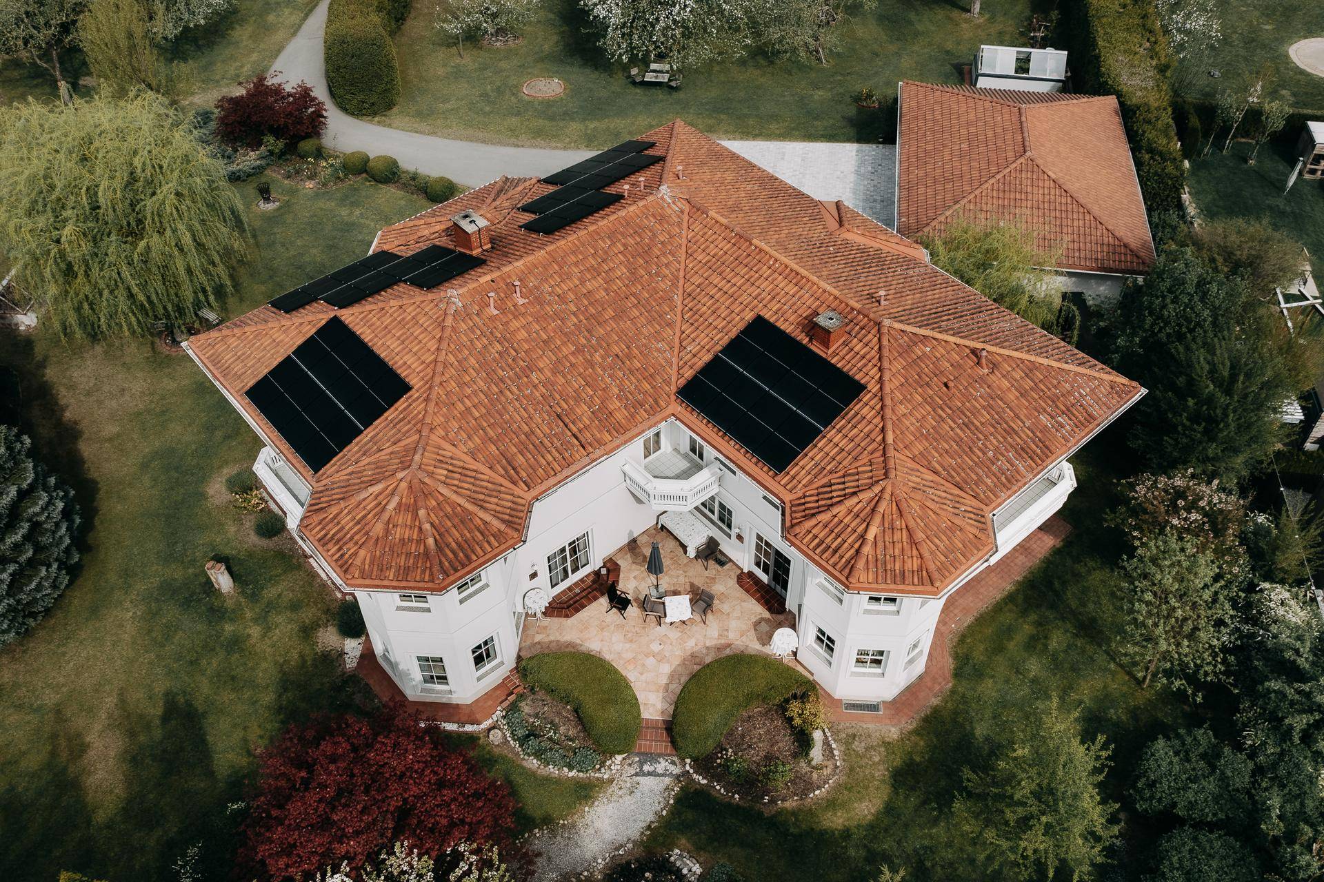 Vogelperspektive des Anwesens mit Photovoltaikanlage auf dem Ziegeldach und weitläufigem Garten.
