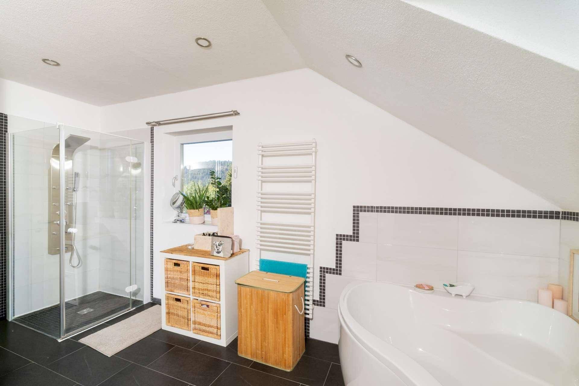 Helles Badezimmer mit großer begehbarer Dusche, Eckbadewanne und beheiztem Handtuchhalter.