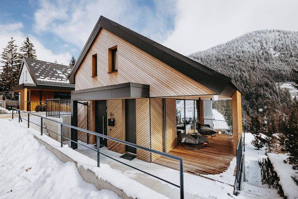 Holzterrasse mit Sitzgelegenheiten und Blick auf die verschneite Berglandschaft.