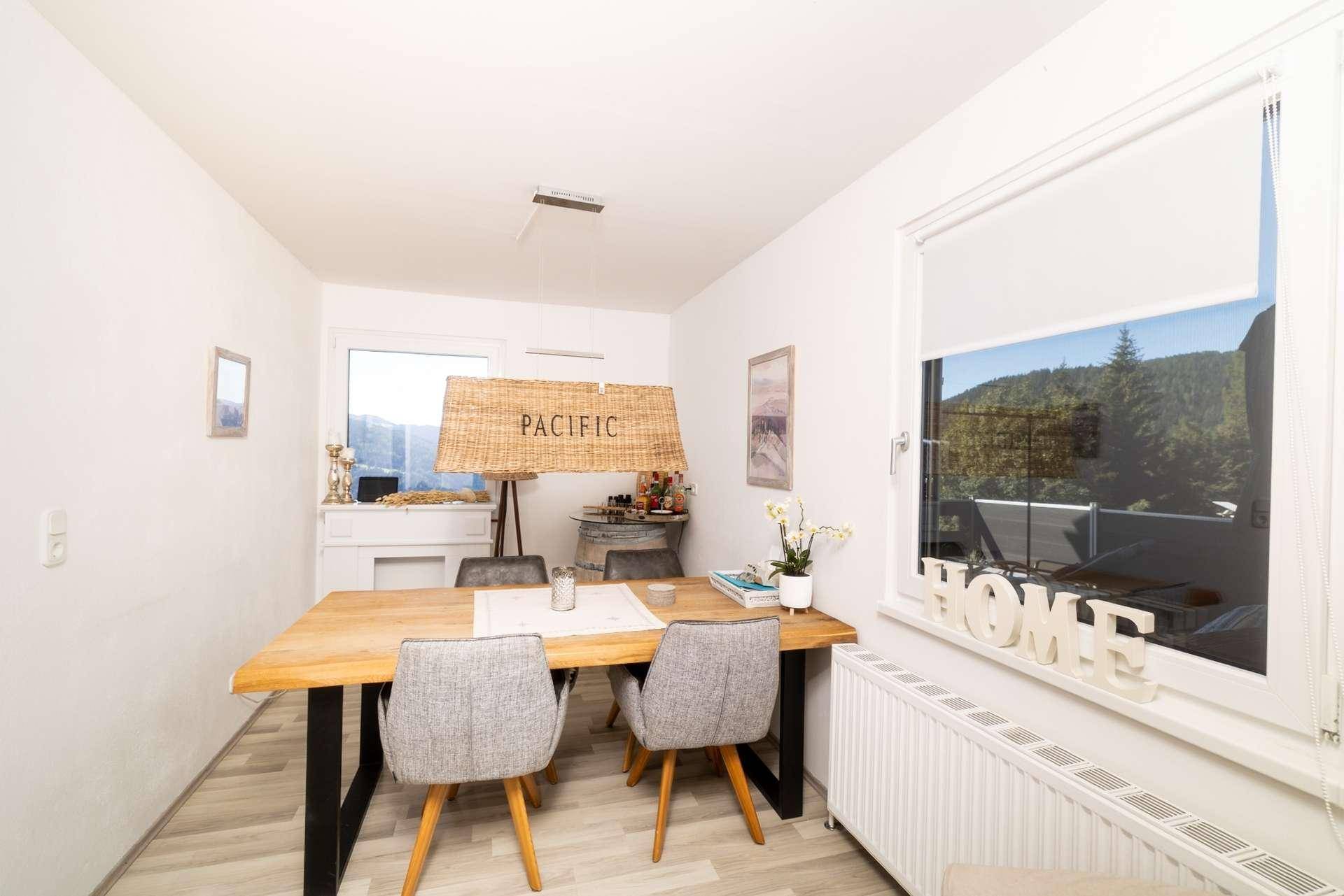 Heller Essbereich mit Holztisch, modernen Stühlen und Blick ins Grüne durch das Fenster.