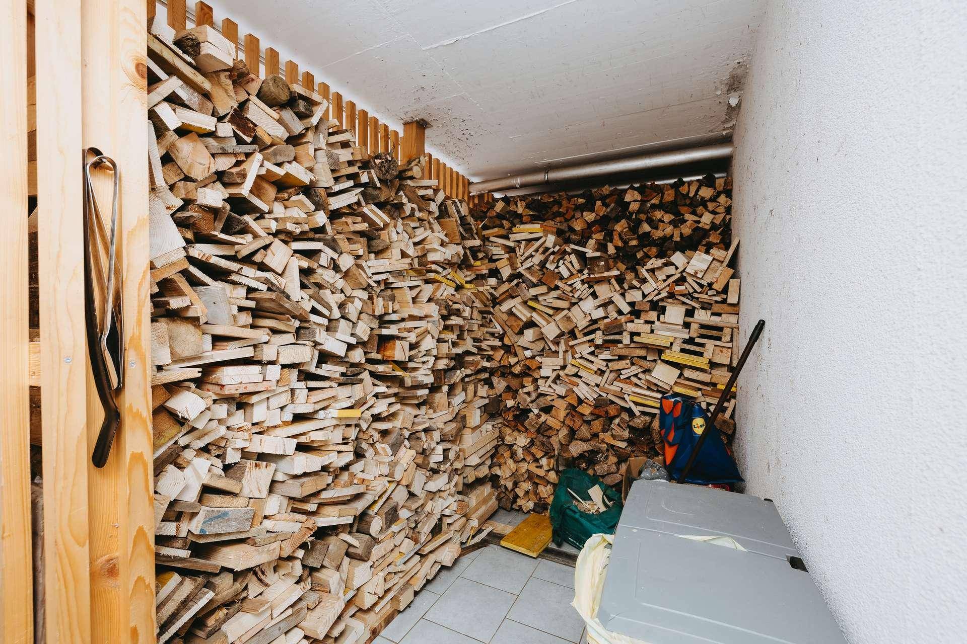 Lagerraum im Keller mit gestapeltem Brennholz für den Ofen und Fliesenboden.