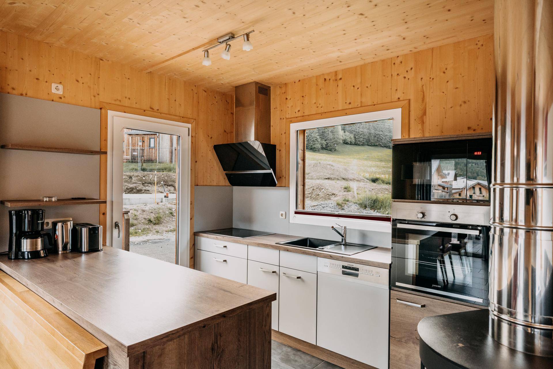 Moderne Küche mit Holzarbeitsplatten, Einbaugeräten und Blick auf die Berglandschaft.
