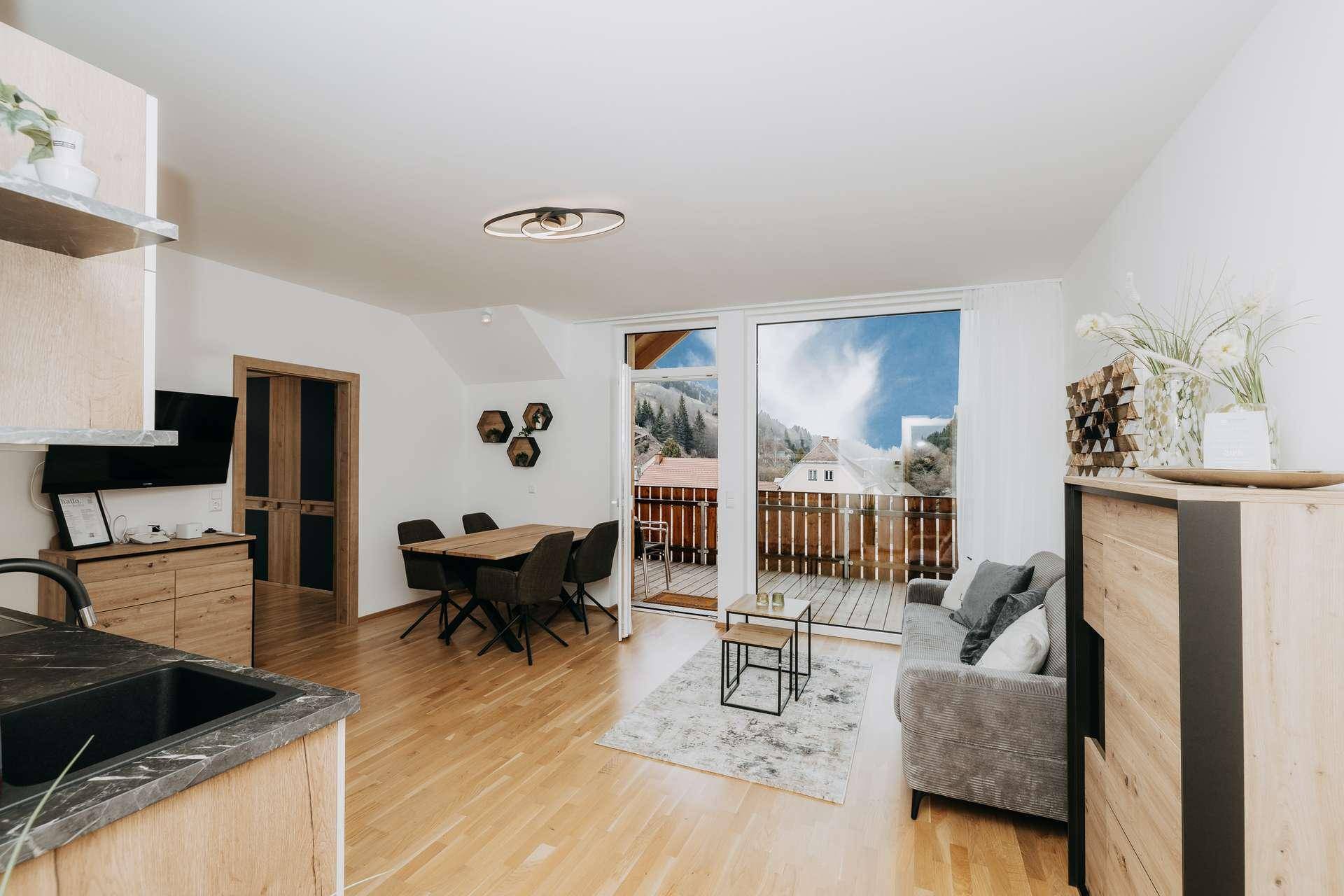 Offener Wohn-Essbereich mit integrierter Küche und direktem Zugang zu einem Balkon mit Bergblick.