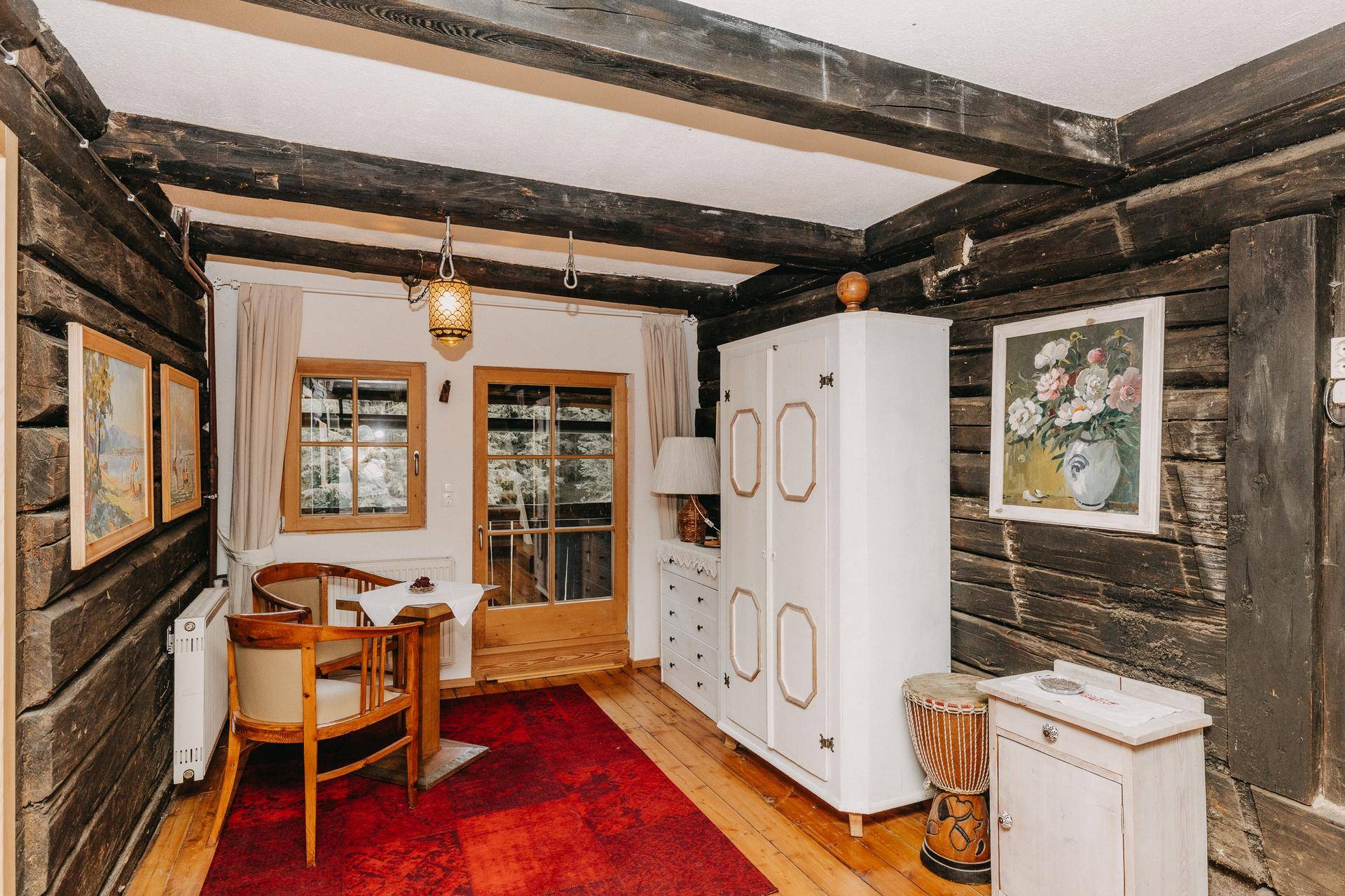 Gemütliches Schlafzimmer mit Holzwänden, Holzbalken und traditionellen Möbeln.