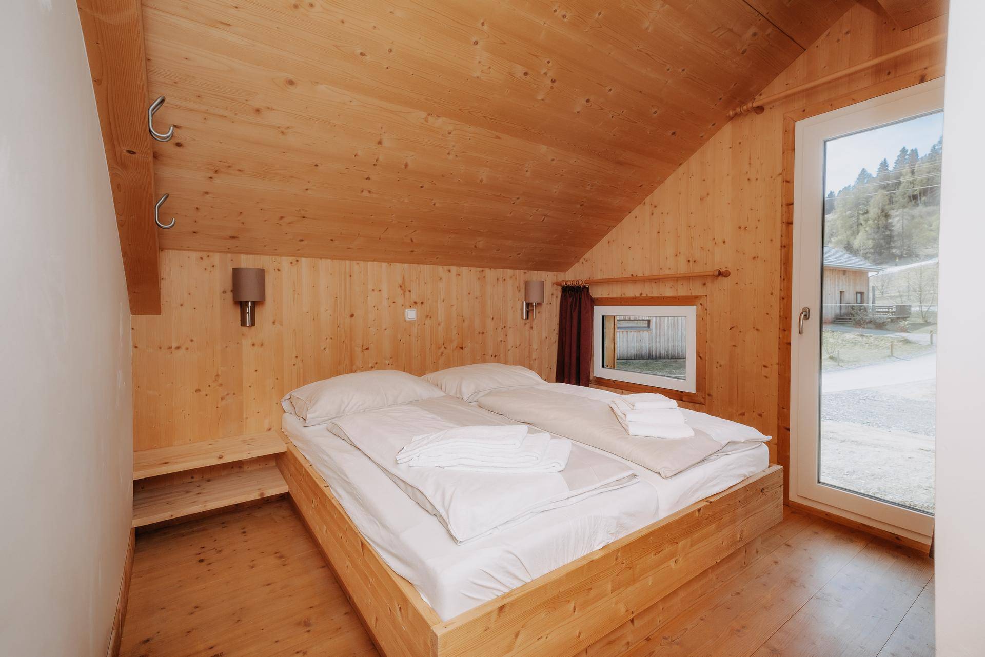 Helles Schlafzimmer mit Holzausstattung, Doppelbett und schrägen Decken im Dachgeschoss.