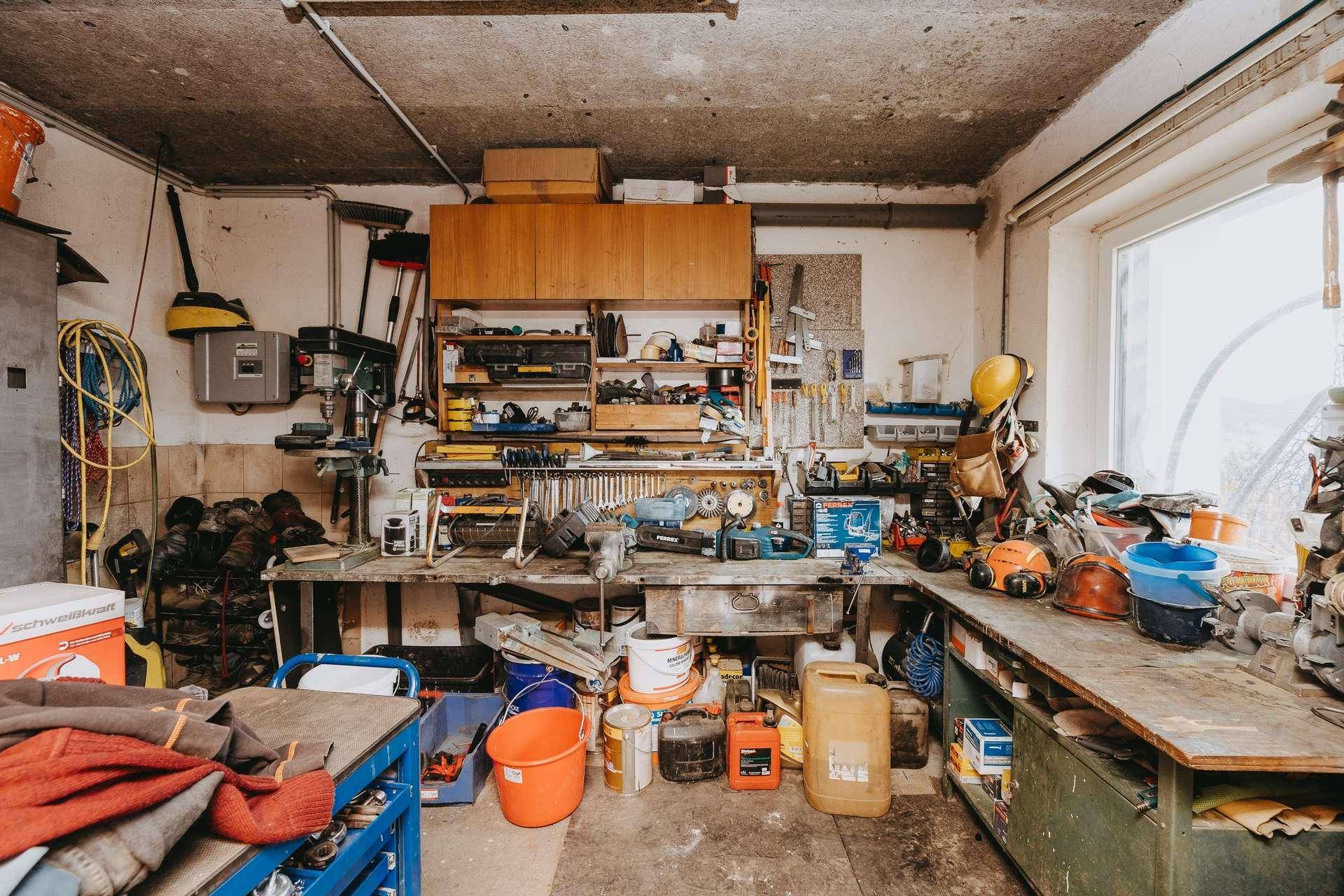 Geräumige Werkstatt mit einer großen Werkbank, vielen Werkzeugen und einem Fenster für Tageslicht.
