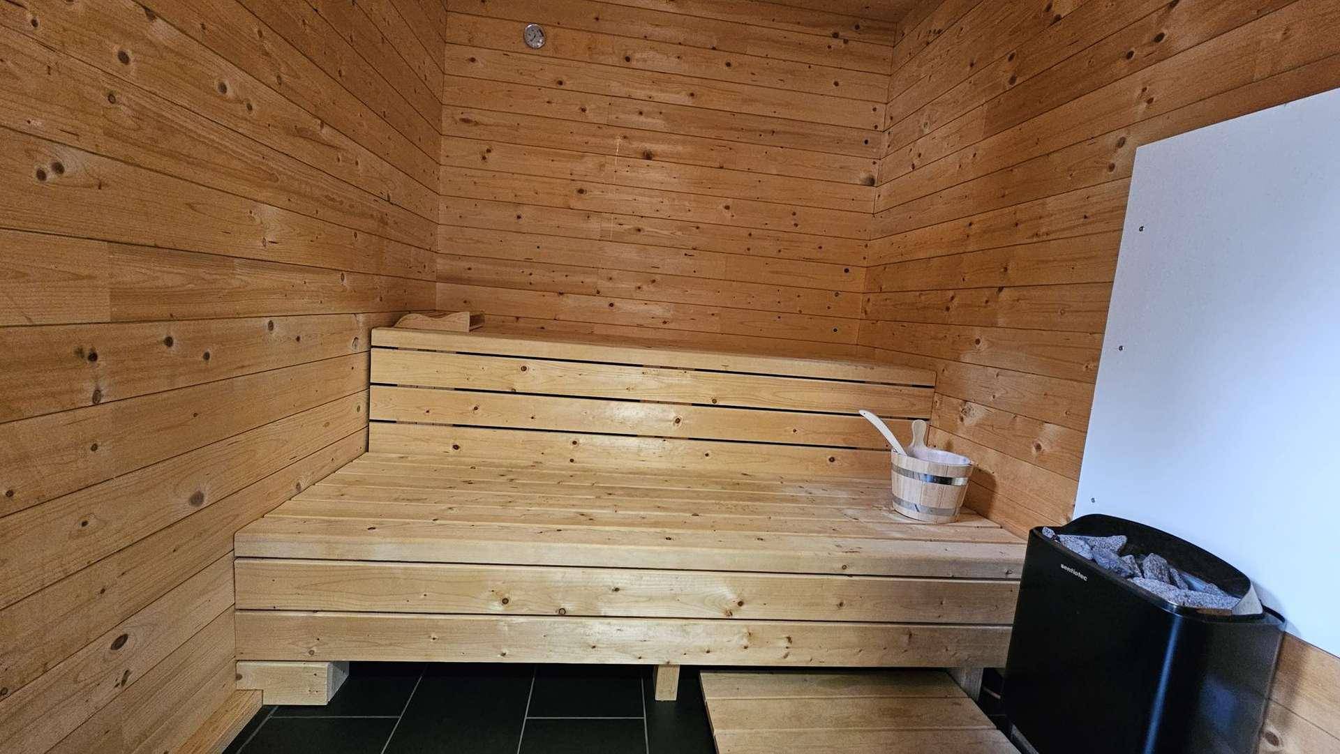 Geräumige Holzsauna mit Sitzbänken und Saunaofen für Entspannung.