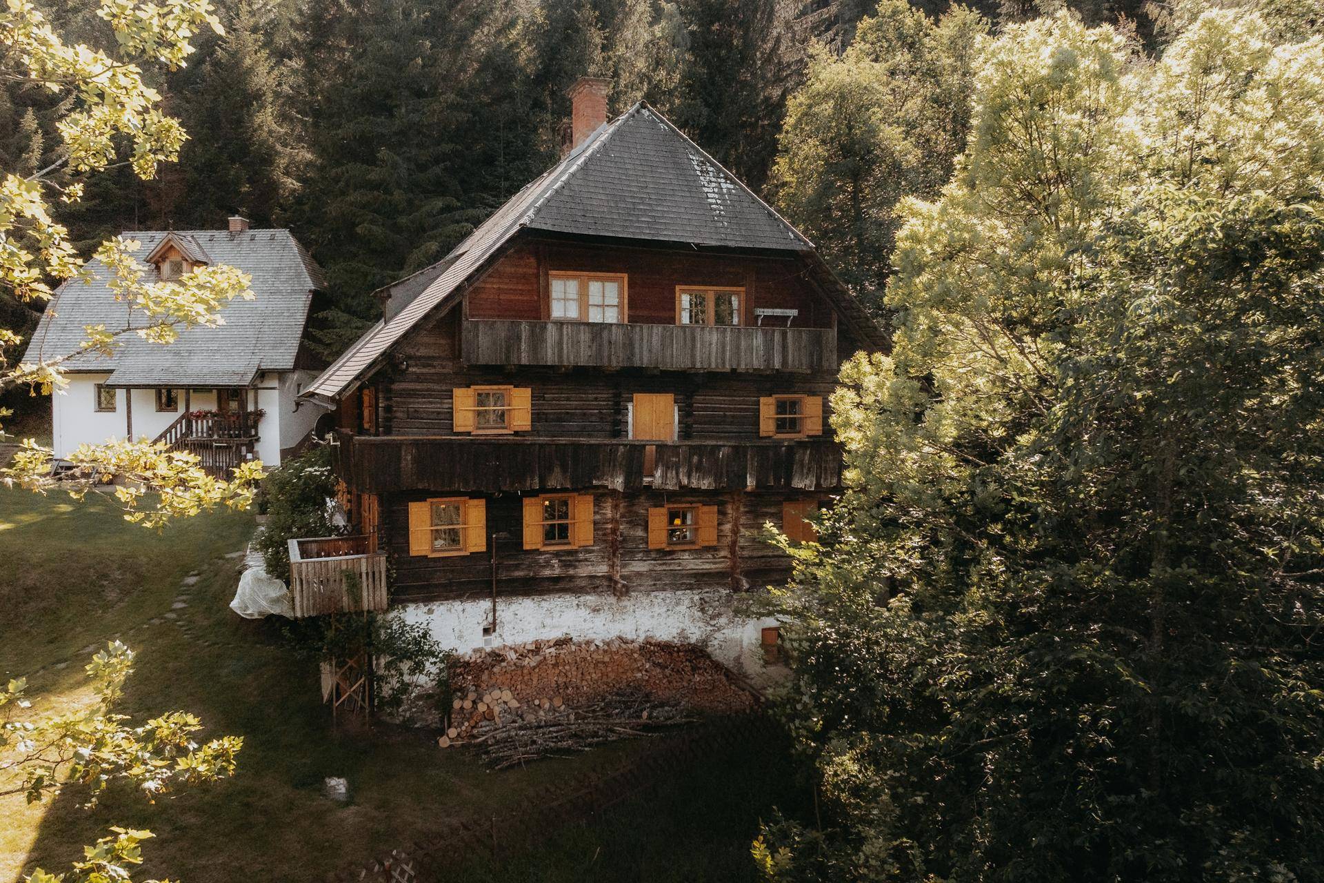 Charmantes Holzhaus mit Balkonen und gelben Fensterläden, eingebettet in eine grüne Landschaft.