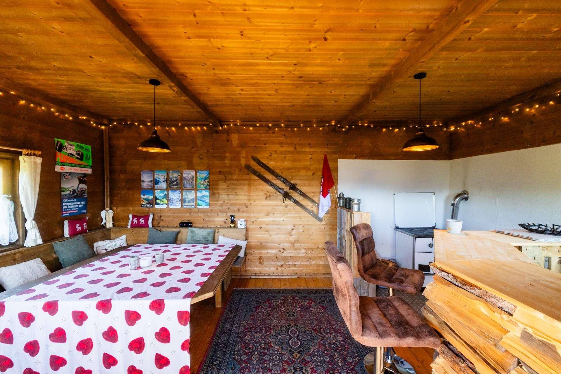 Geräumiger Essbereich in einer Holzhütte mit langer Sitzbank, Holzbar und Kaminofen.
