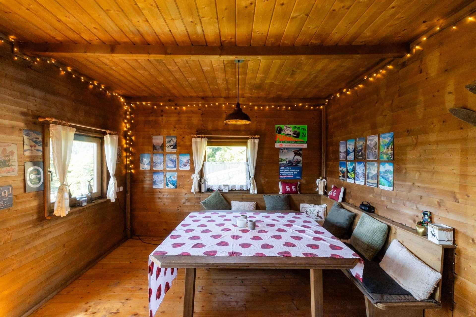 Gemütlicher Essbereich in einer Holzhütte mit Lichterketten, rustikalen Möbeln und Holzwänden.