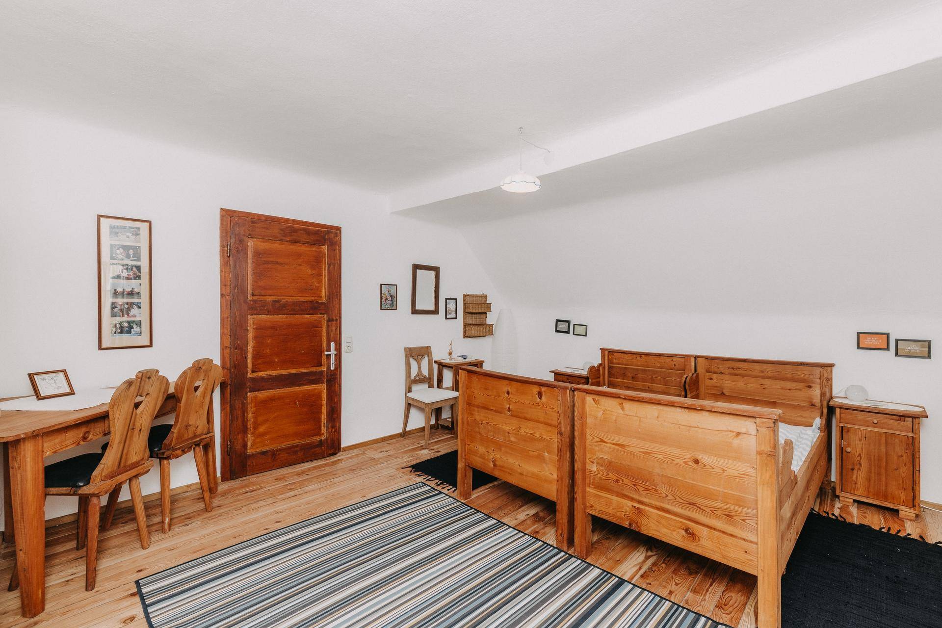 Helles Schlafzimmer mit zwei Holzbetten, Holzboden und traditionellem Schreibtisch.