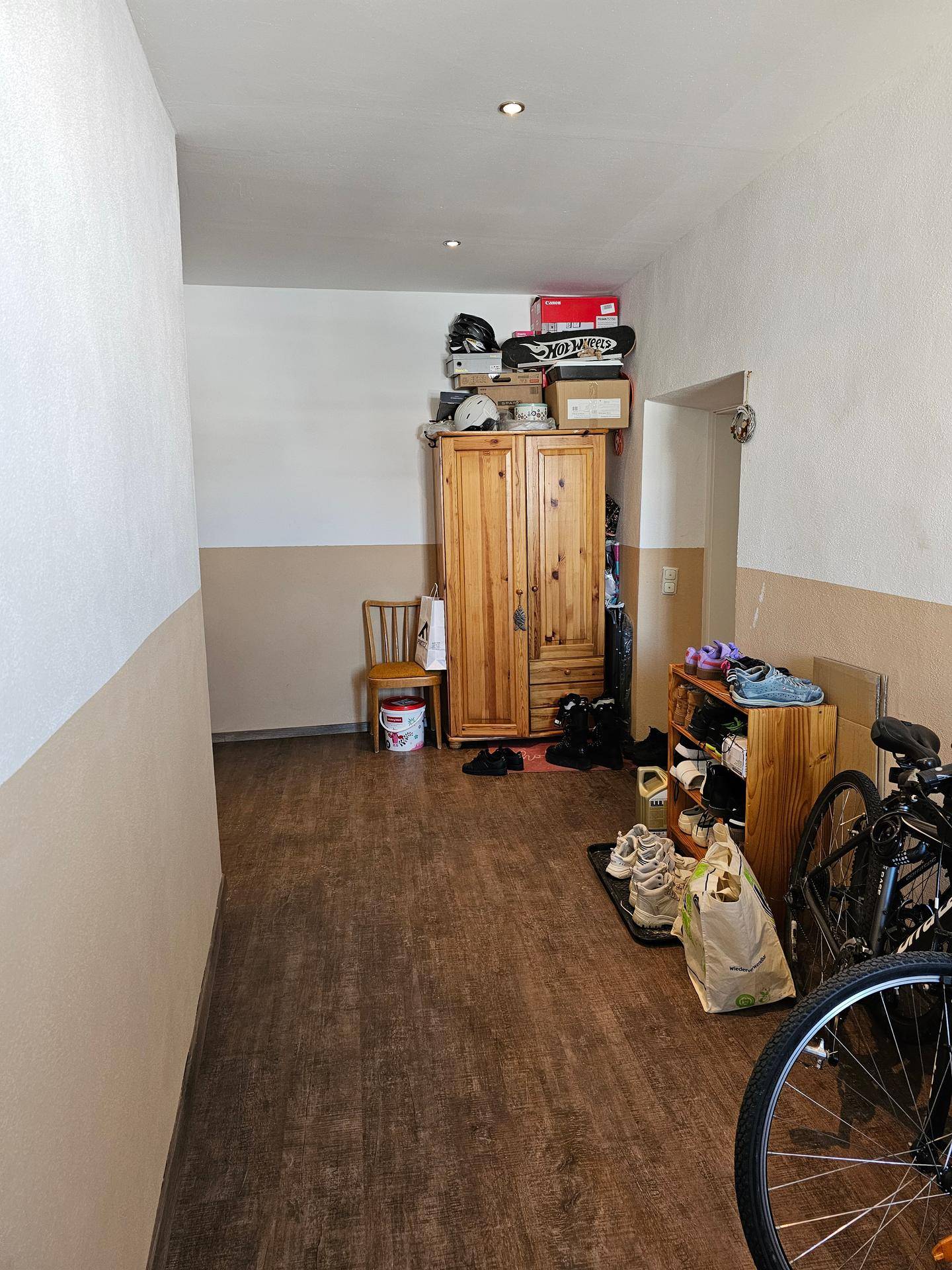 Geräumiger Flur mit dunklem Laminatboden, Stauraum und Fahrrädern an der Seite.
