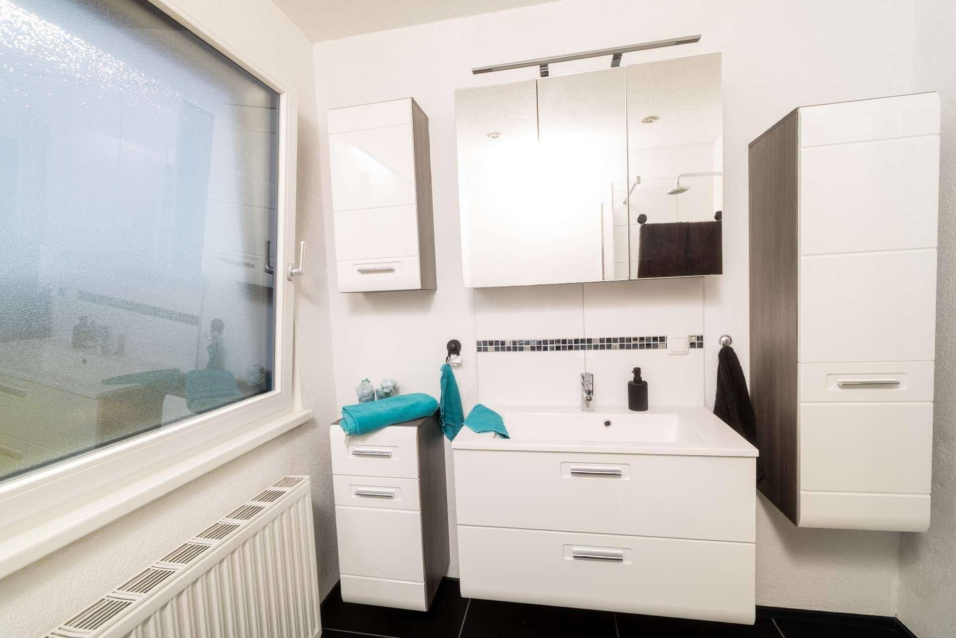 Modernes Badezimmer mit Einzelwaschbecken, Spiegelschrank und Duschkabine.