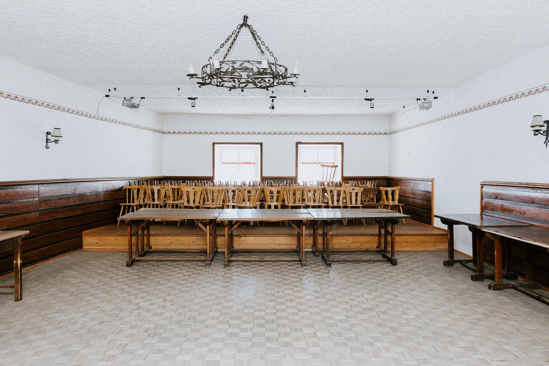 Großer Veranstaltungsraum mit vielen Holztischen und Stühlen, bereit für eine Veranstaltung.
